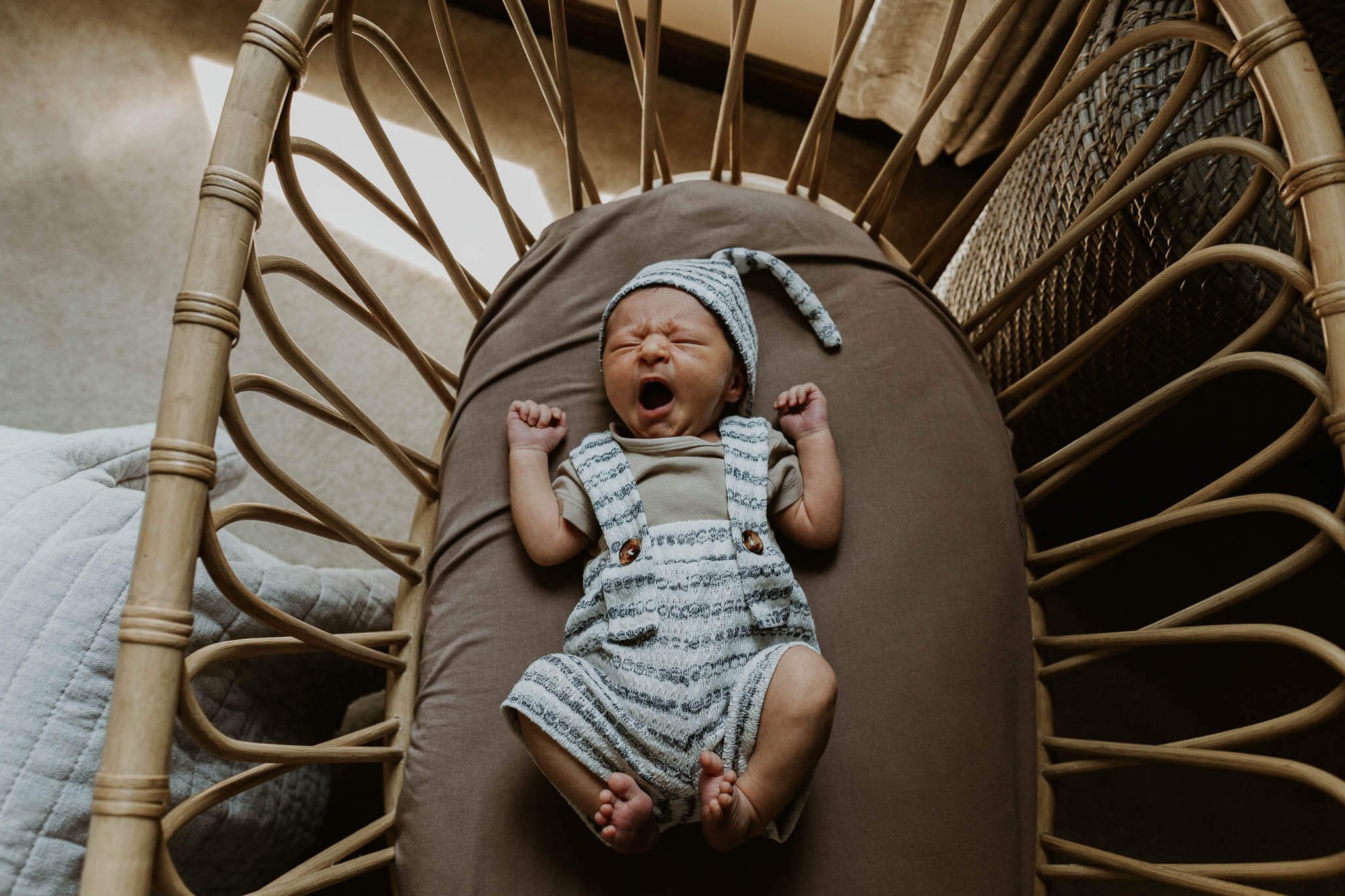 A sleepy newborn yawns in his bassinet