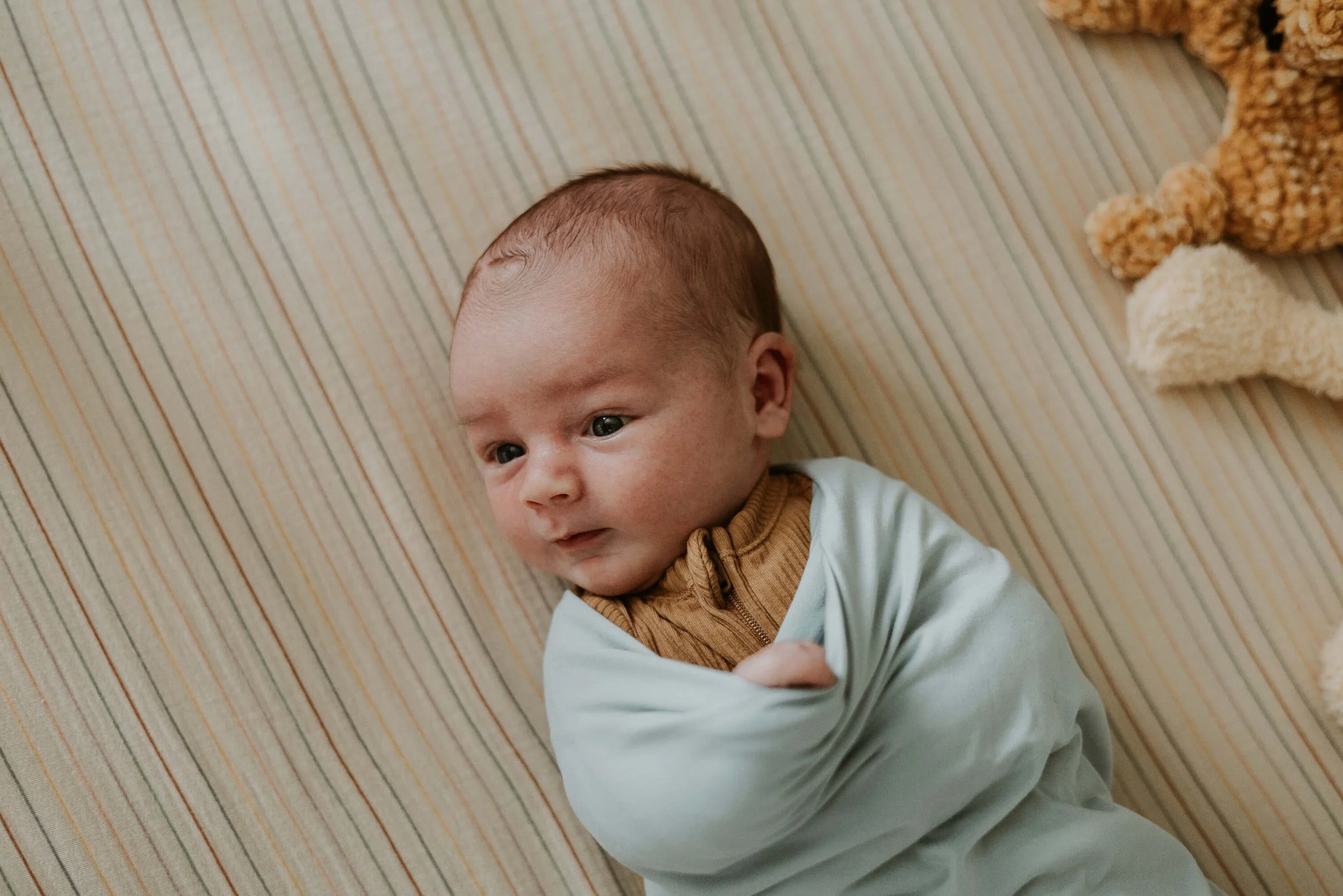 A newborn lays awake in his crib, quietly taking in his surroundings
