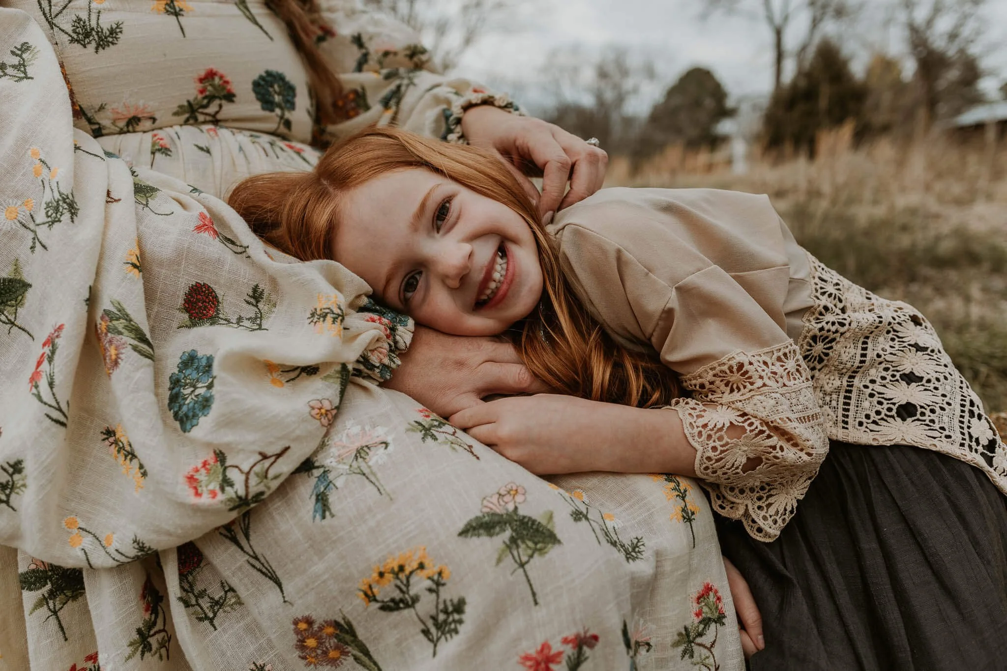 A smiling daughter snuggles on her mothers lap