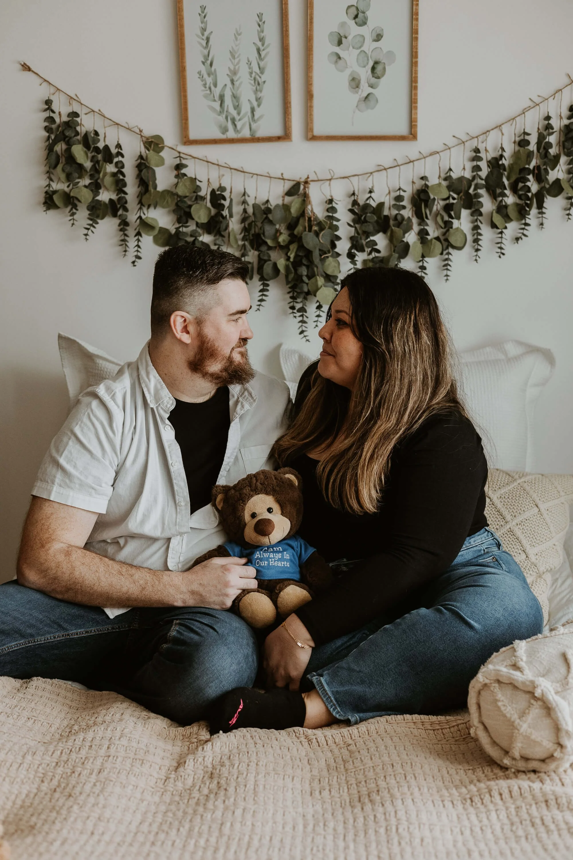 A couple tenderly hold a teddy bear that signifies the loss they share of their first son