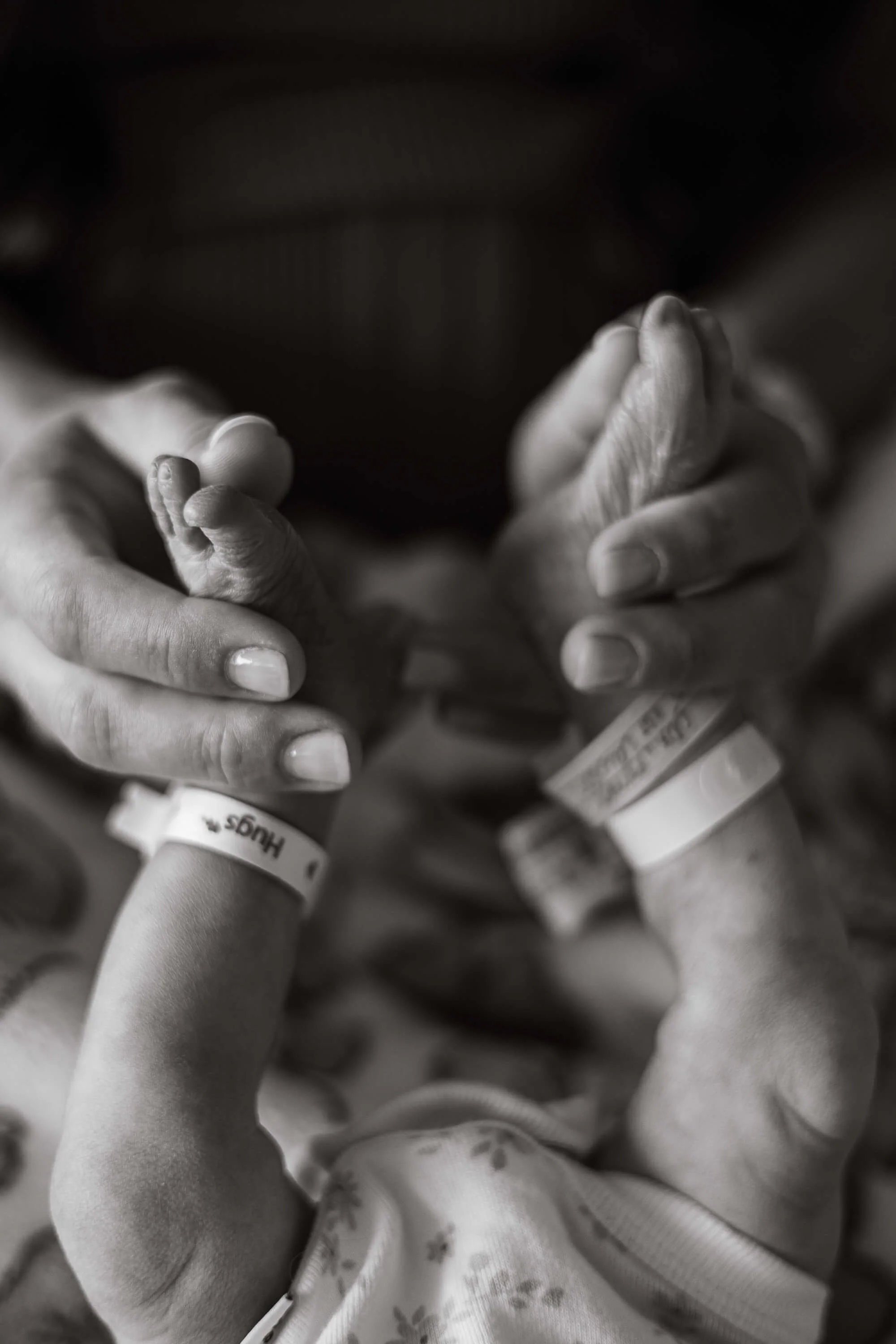 A black and white detail image of a newborn's mother admiring her daughter's feet