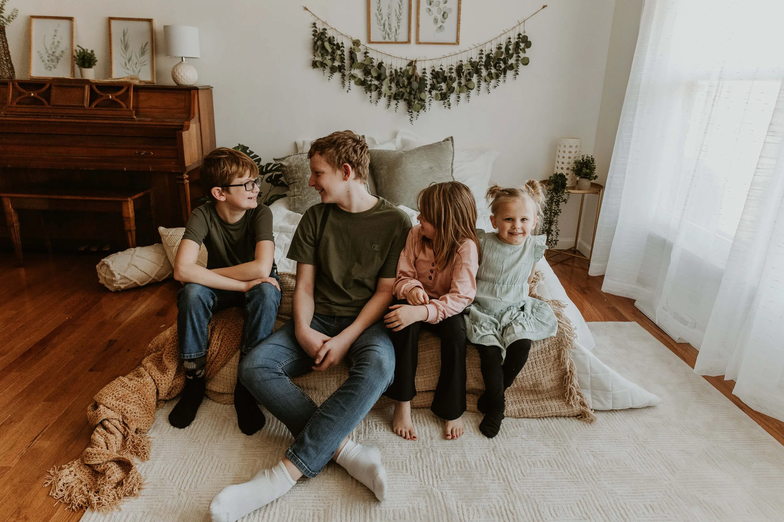 Four siblings sit at the edge of a bed during their studio session in Bloomington IL