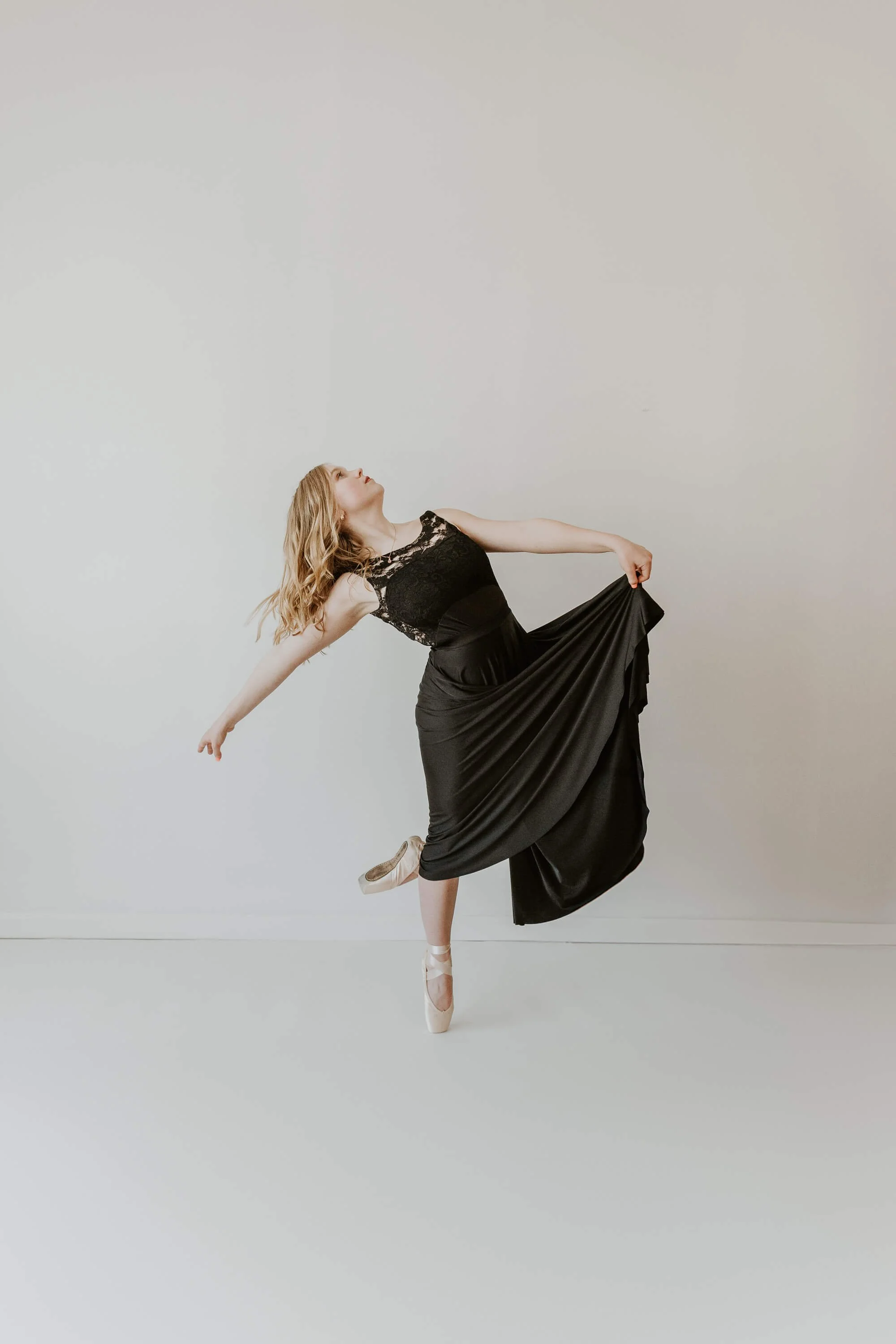 High school senior Katy holds her flowy dance skirt as she dances in her pointe shoes.