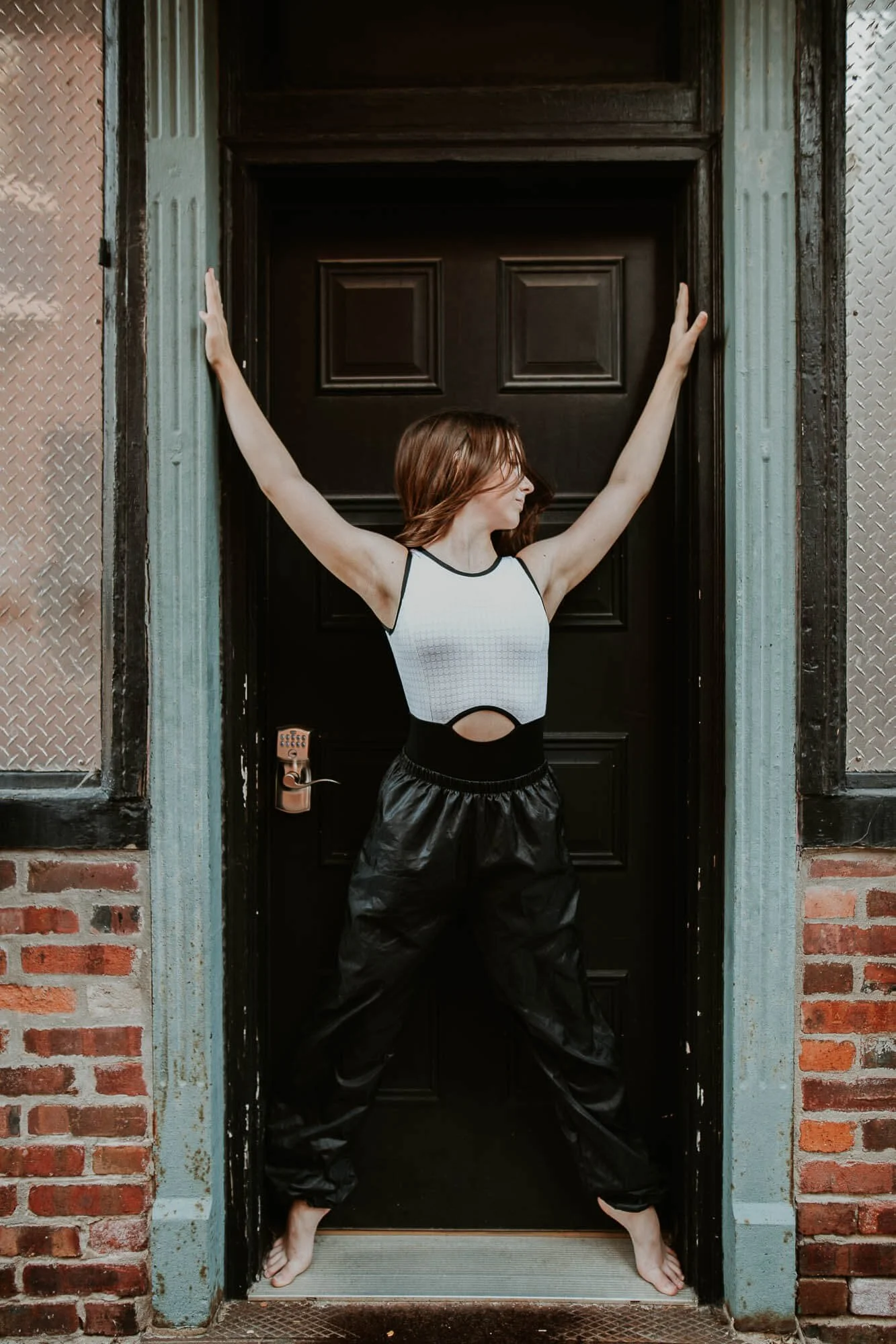 A dancer uses her body to take up the entire doorway to demonstrate her power and strength.