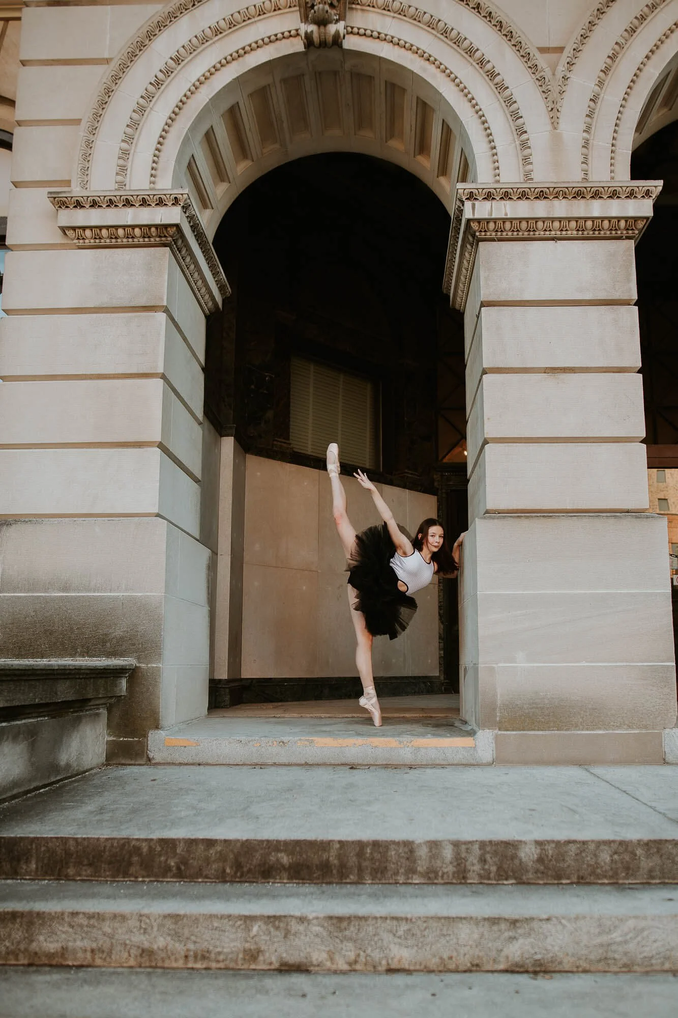 Under the arch outside McLean County History Museum, a dancer effortlessly stretches one leg straight into the air