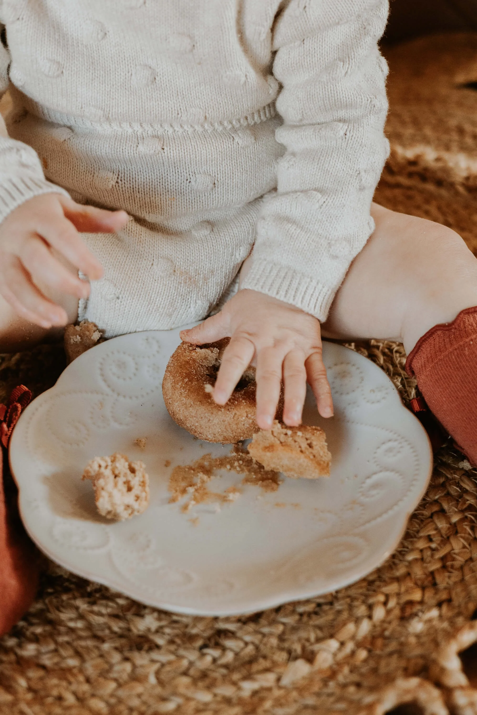 A one year old celebrates her birthday with a cake smash, fisting a delicious donut