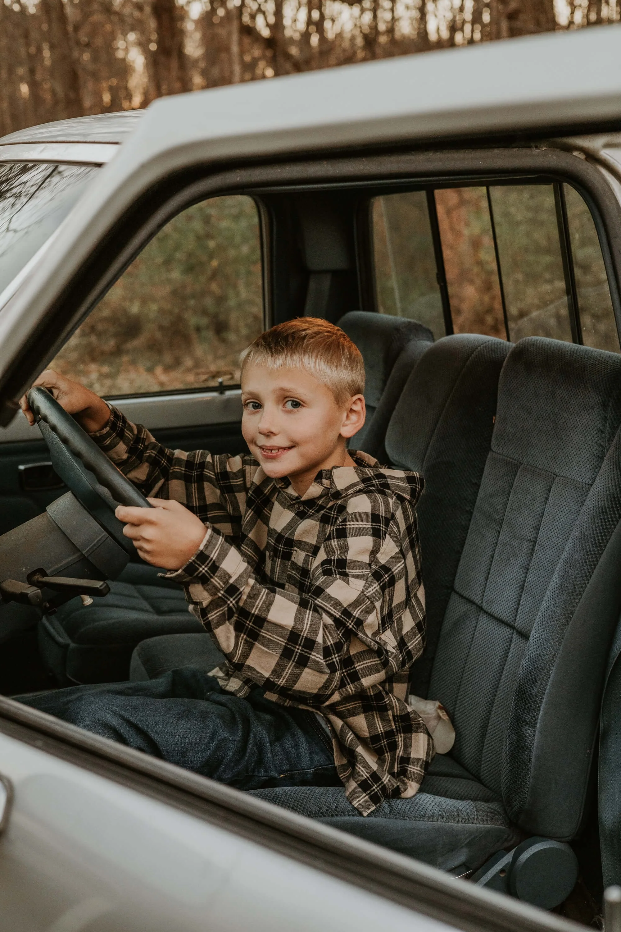 A close up of a boy pretending to drive his uncle's pick up truck