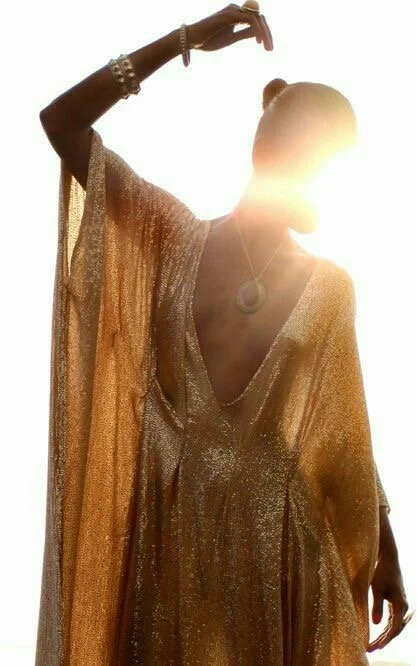 A golden-robed woman standing in bright sunlight, her figure glowing as light pours through the fabric, symbolising prophetic calling, divine awakening and the radiant authority of a remnant prophet.