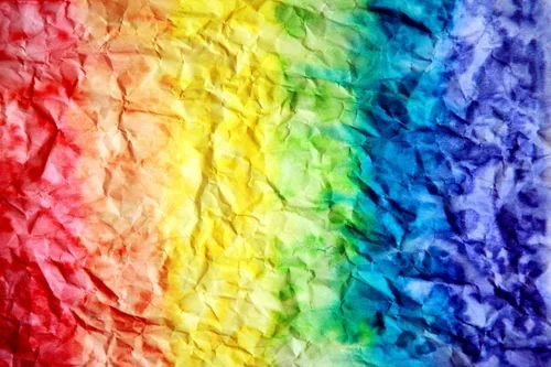 A crumpled piece of paper or fabric which is the colours of the rainbow (from left to right)