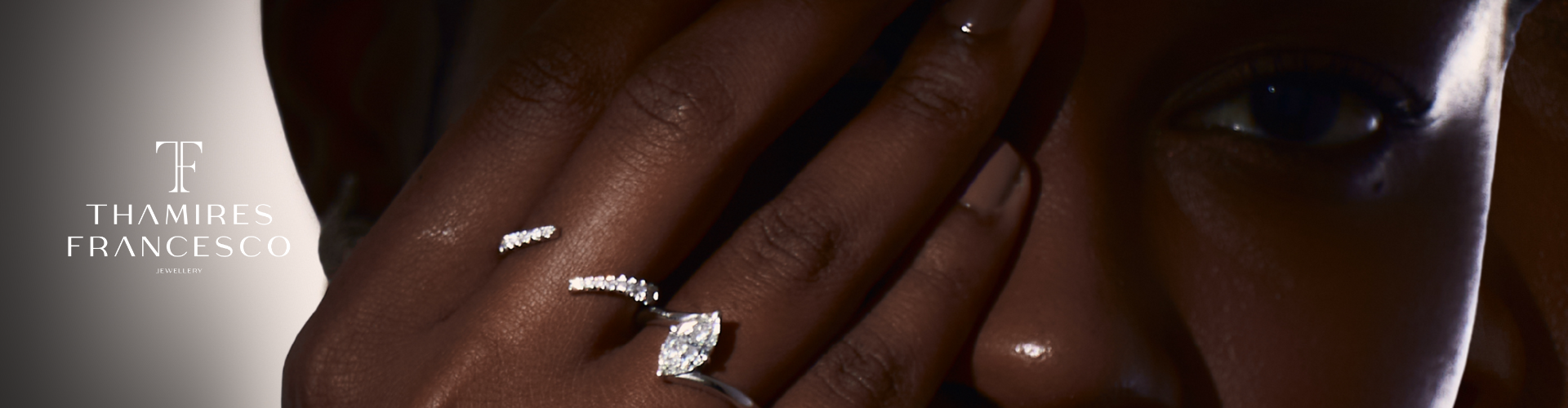 Pessoa com pele escura usando um anel de diamantes e uma aliança, cobrindo parte do rosto com a mão