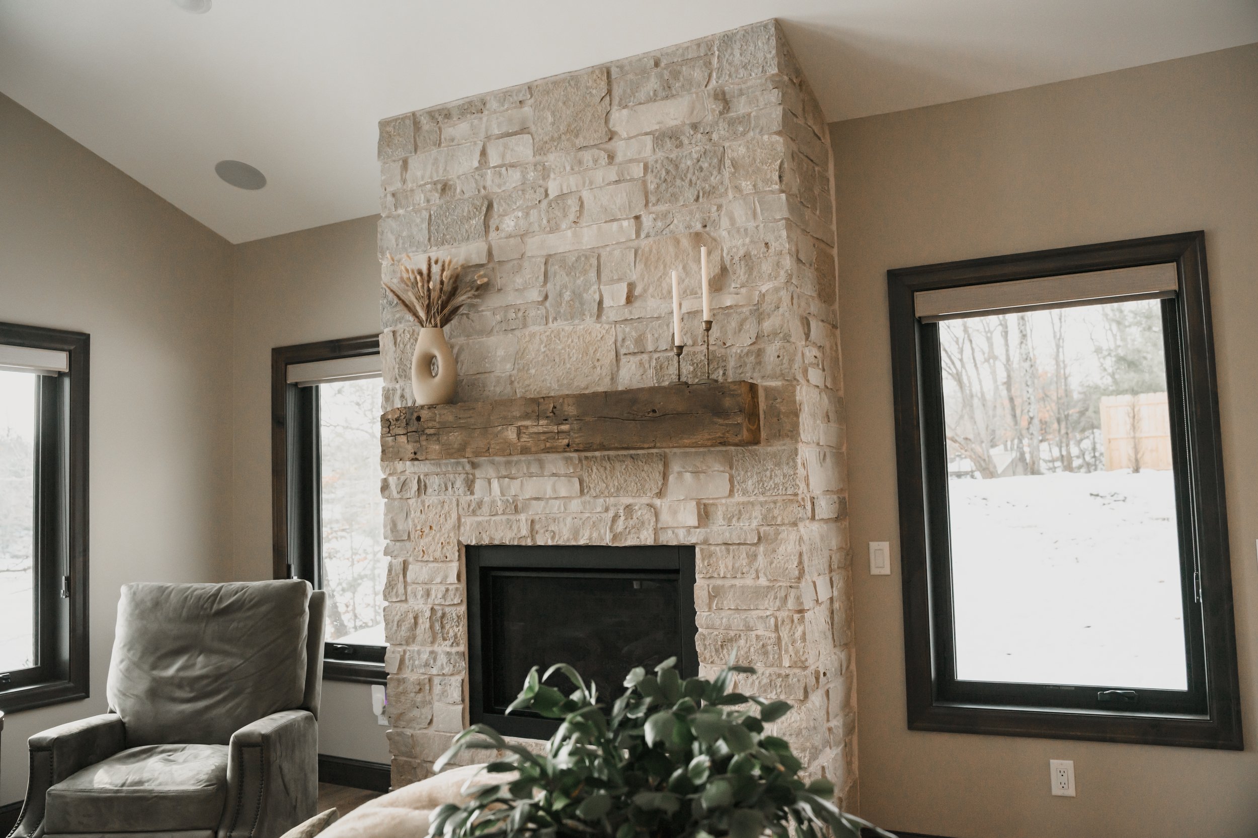 Floor-to-ceiling stone fireplace with wood mantel in a finished residential living space.