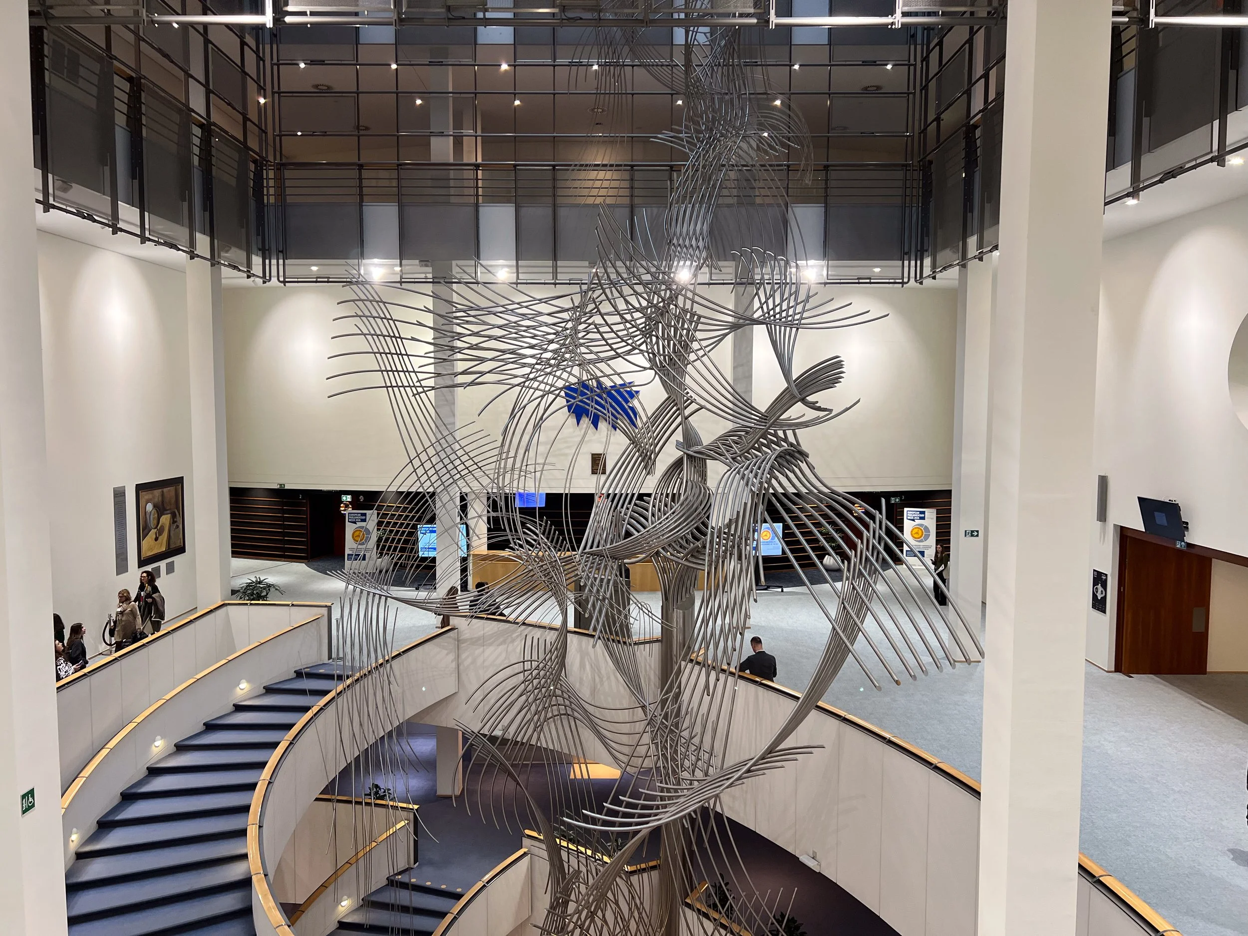 "Confluences," a kinetic sculpture by Belgian artist Olivier Strebelle, is located in the lobby of the European Parliament. The trunk represents unity, the branches represent the individual member states, and the way the movement of one branch trigge