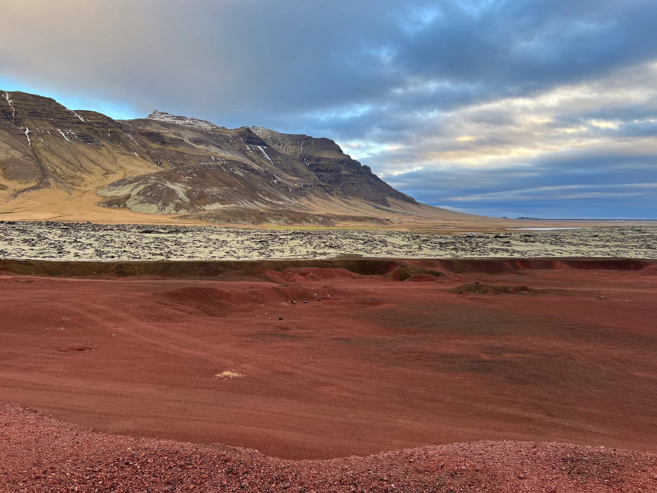 The iron-rich red lava in the foreground is surrounded by the more common grayish-black lava, covered by moss. It seems that moss thrives on lava rock because it is porous and moisture-retaining while also allowing air flow.