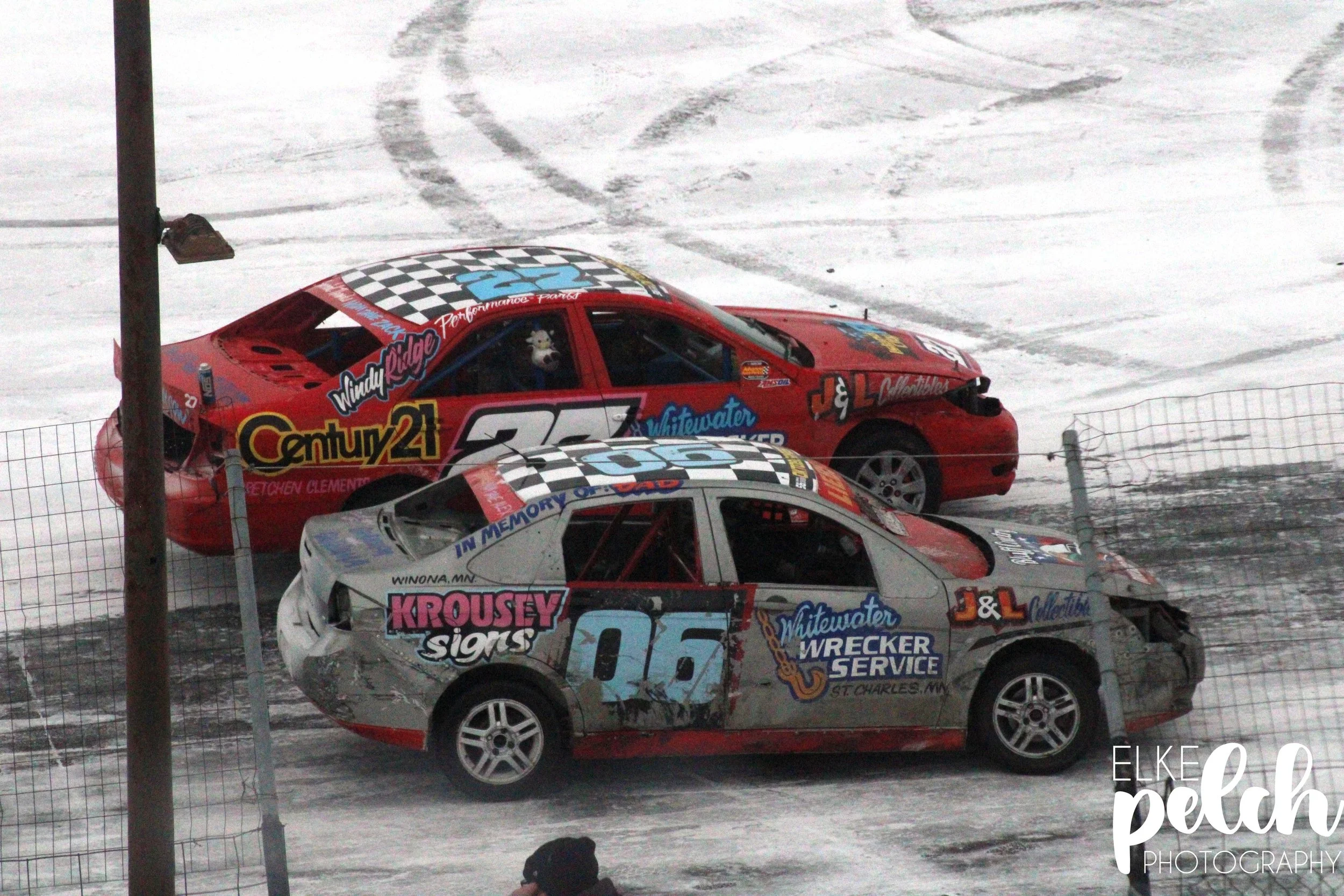 A red 27 car and a grey 06 car park next to each other during a winter race.