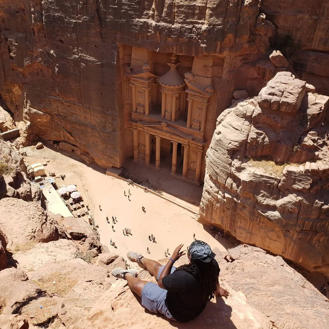 A Black traveler sitting in front the monastery in Petra Jordan.