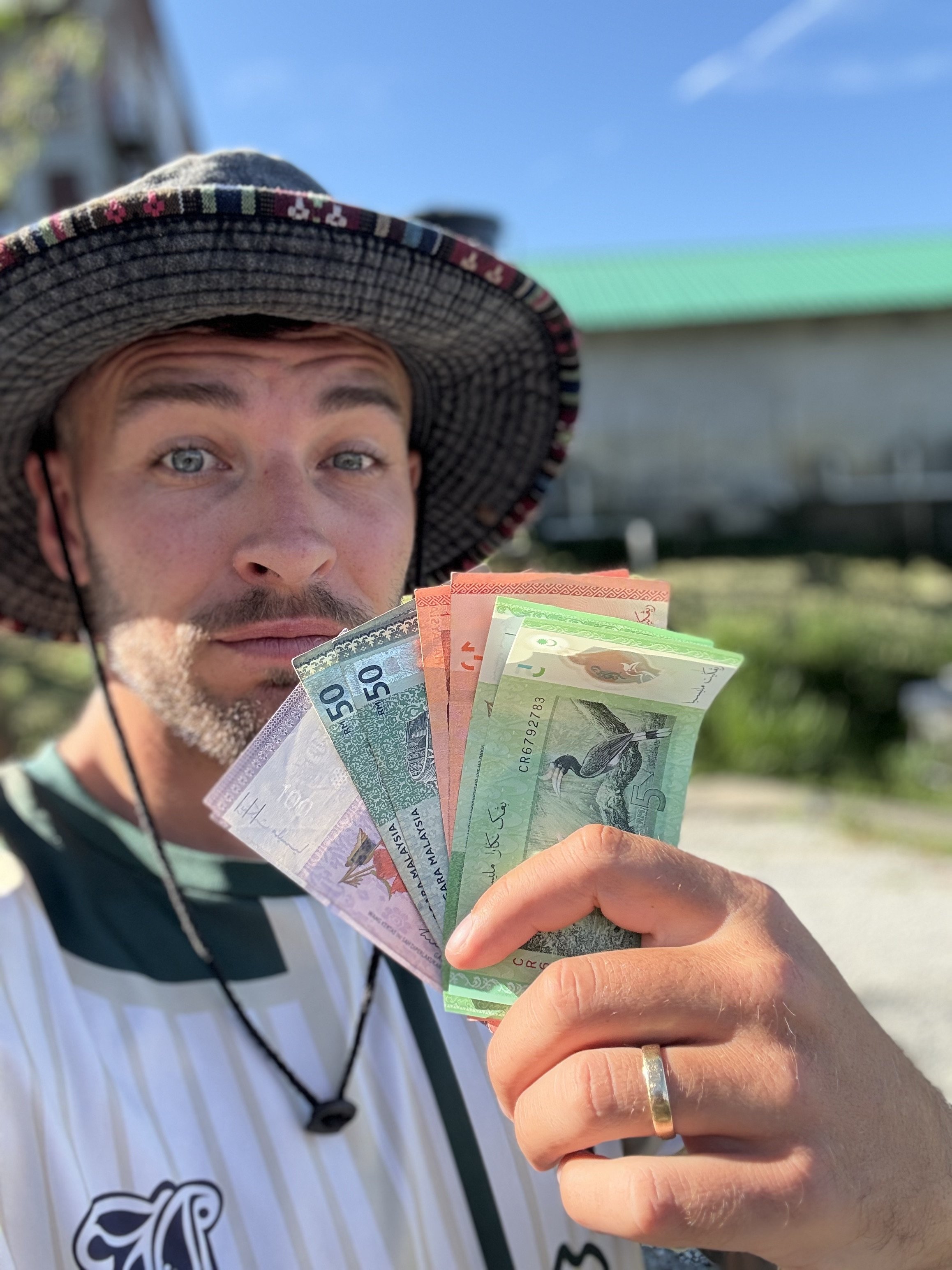 Joe holding up money showing how much we get paid as digital nomads travelling full-time