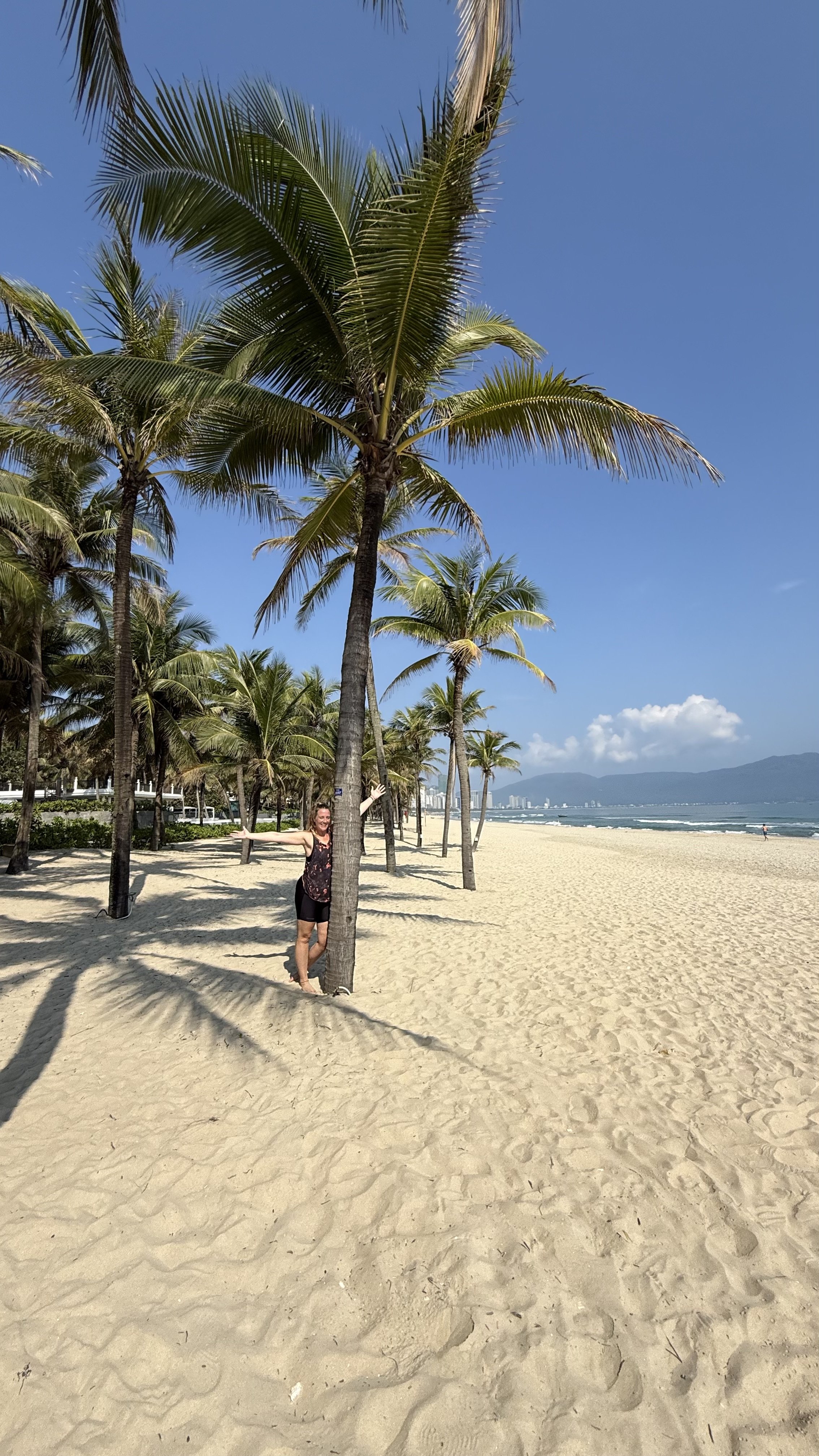 Emma, Smiths On Tour walking down the beach in da nang, vietnam under a palm tree