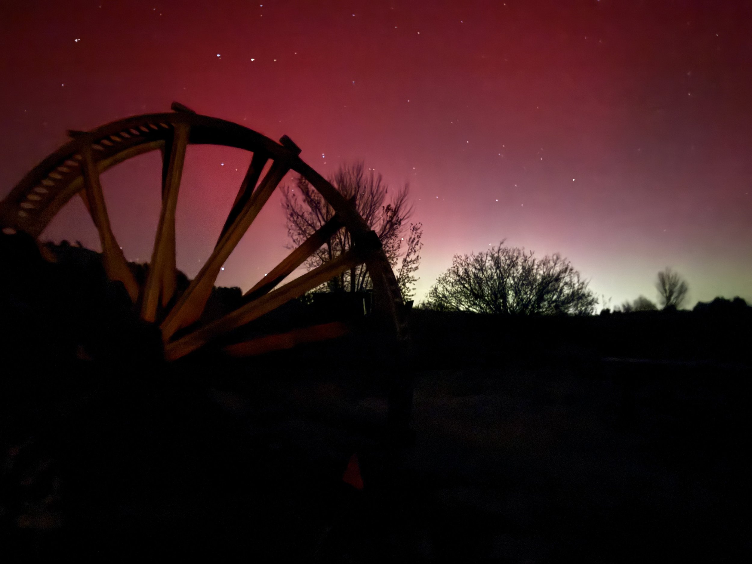 Pink sky behing rustic wagon wheel at Lost Pond wedding venue near Canon City Colorado