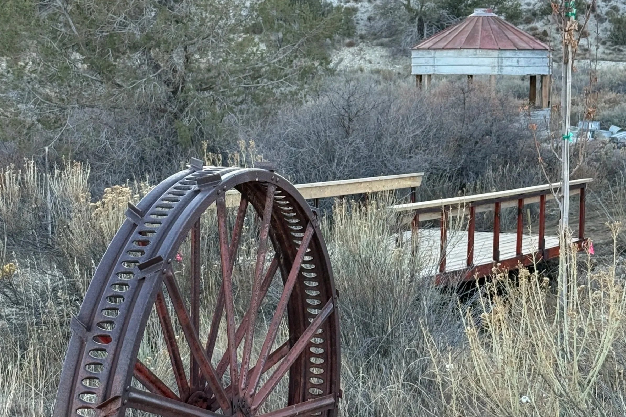 A rustic wagon wheel in front of a bridge over the waterfall at Lost Pond wedding venue near Canon City, Coloraodo