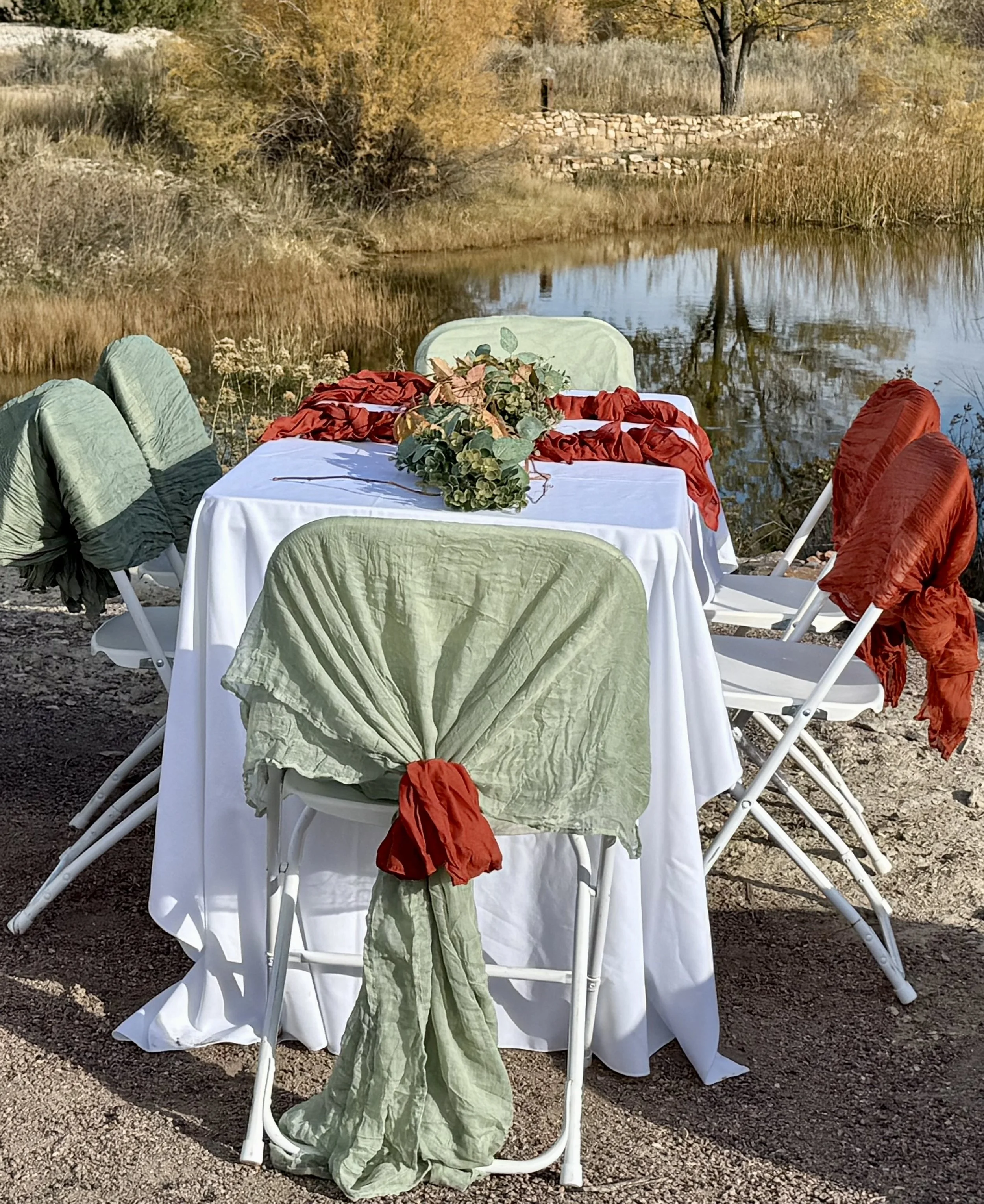 Sage green and burnt orange rust wedding reception by the water at Lost Pond wedding venue near Colorado Springs, Colorado.
