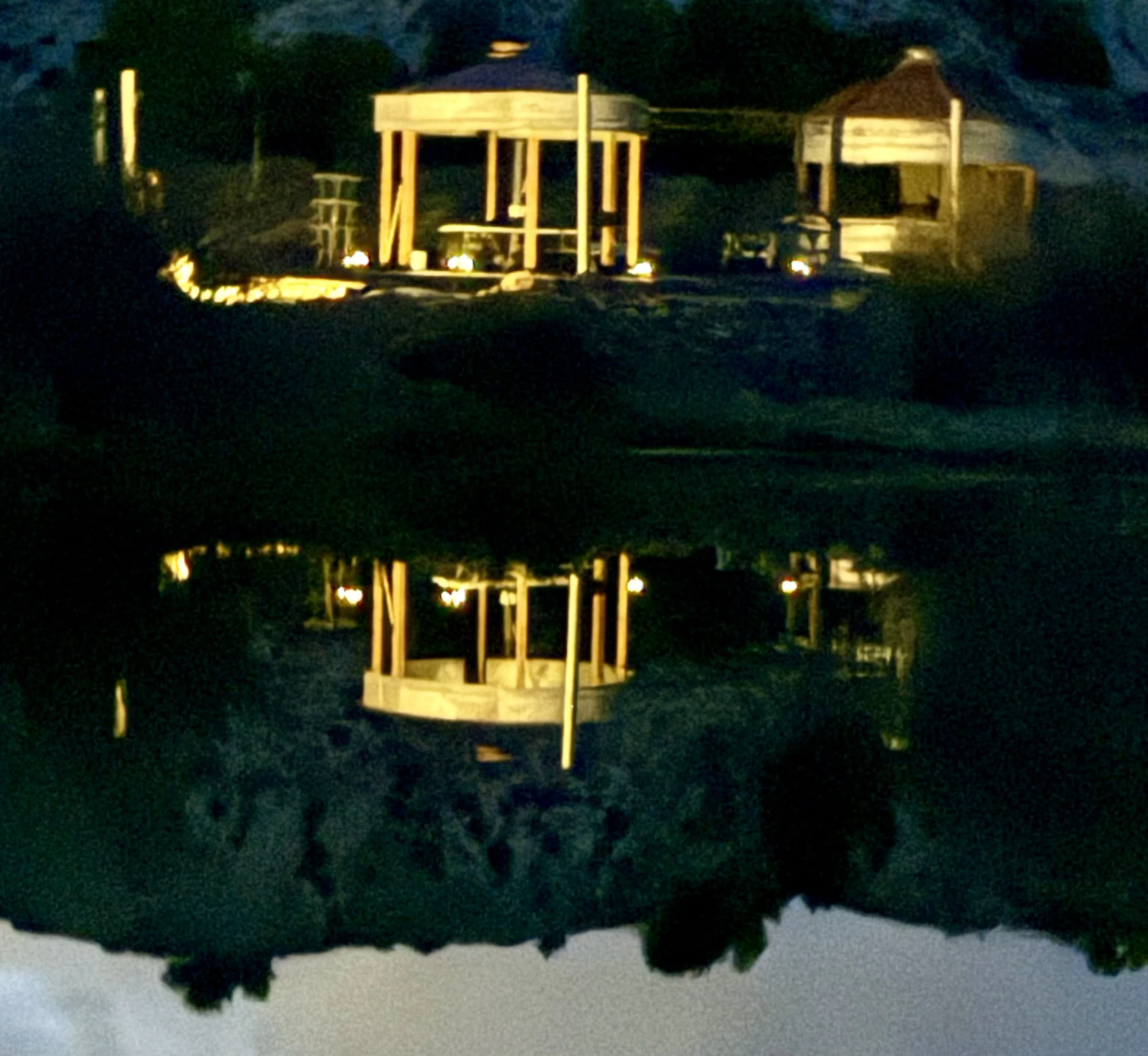 a reflection of the ceremony area at night reflected in the pond at Lost Pond wedding venue near Canon City, Pueblo, Colorado Springs, and Florence, Colorado.