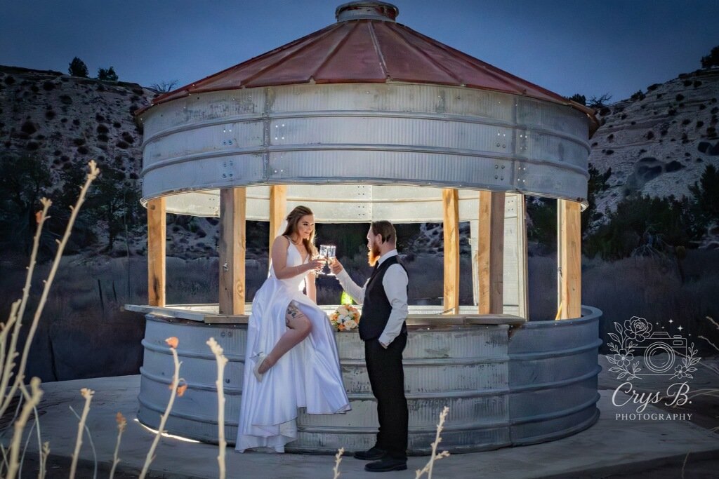 Bride and groom having champagne toast at wedding reception at the silo grain bin bar at Lost Pond a rustic wedding venue near Pueblo, Colorado.