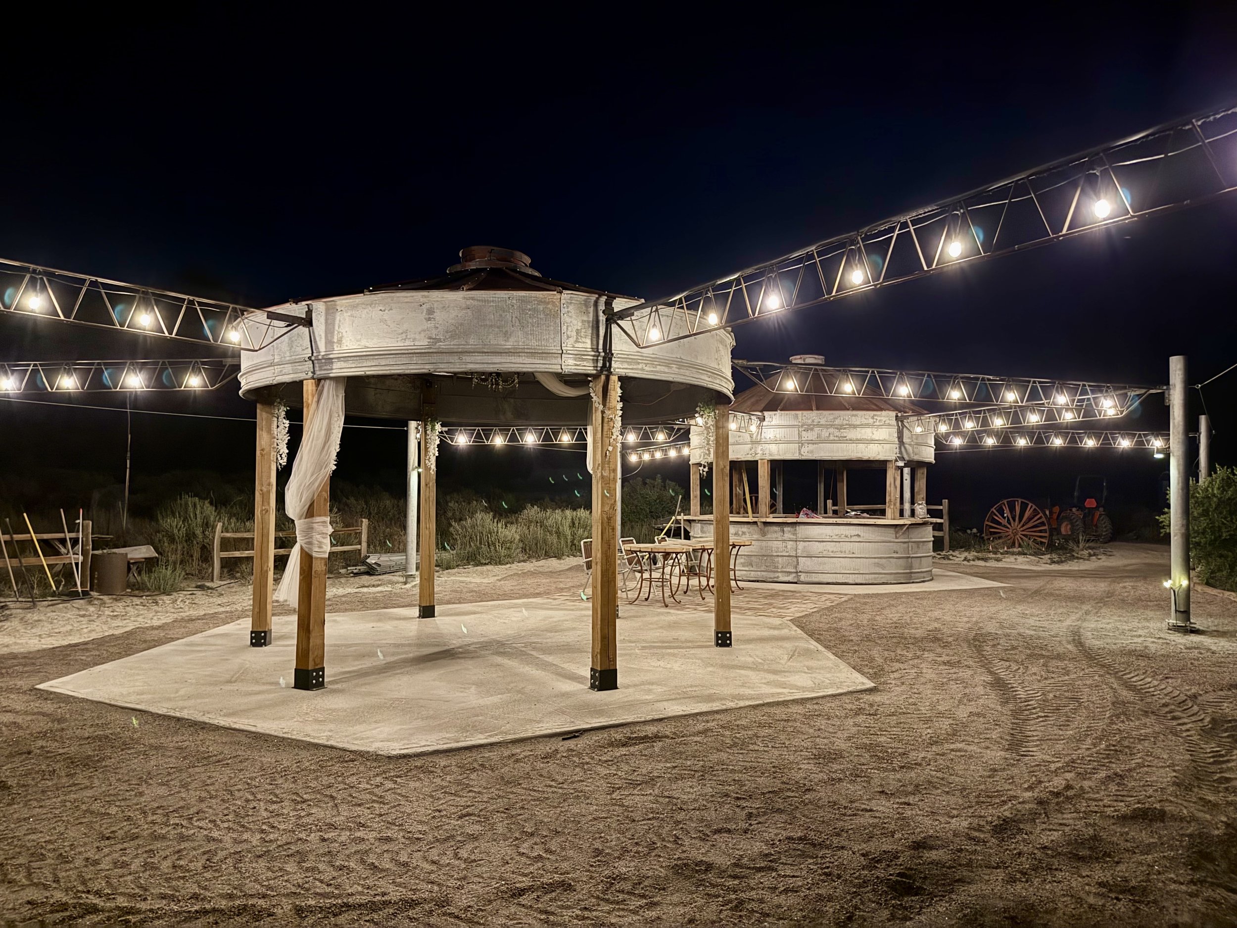 A rustic outdoor wedding reception pavilion illuminated by string lights at night under the stars with romantic lighting at Lost Pond wedding venue between Canon City and Pueblo, Colorado.