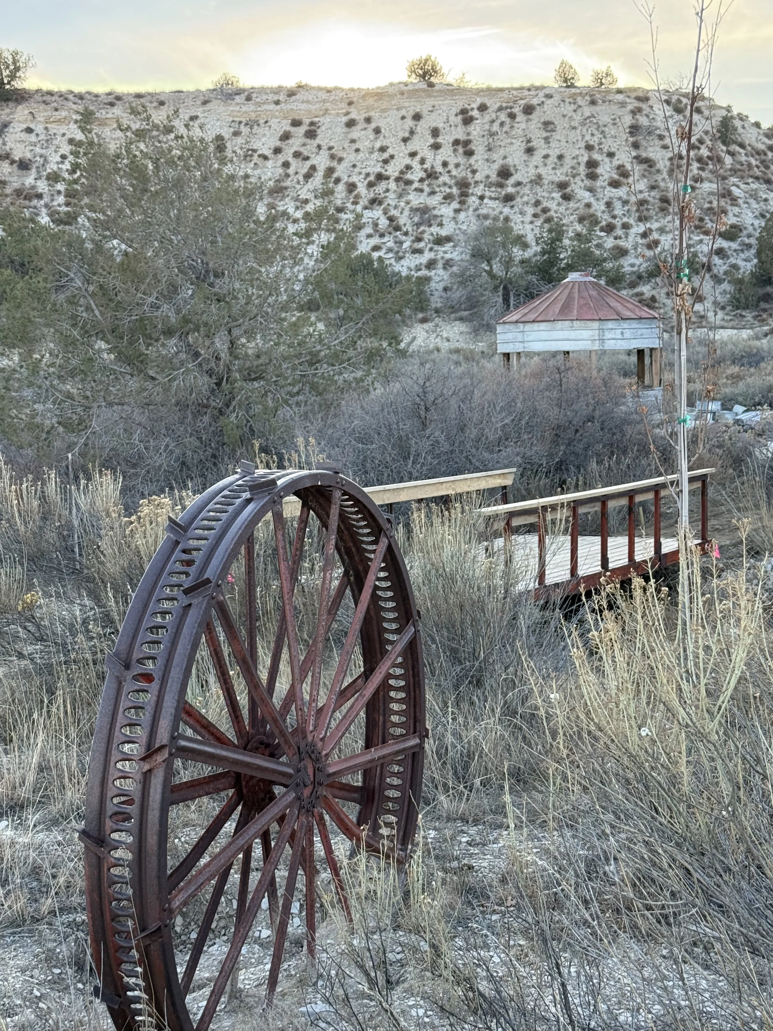 Rustic wagon wheel and bridge over waterfall at Lost Pond wedding venue near Colorado Springs, Colorado.