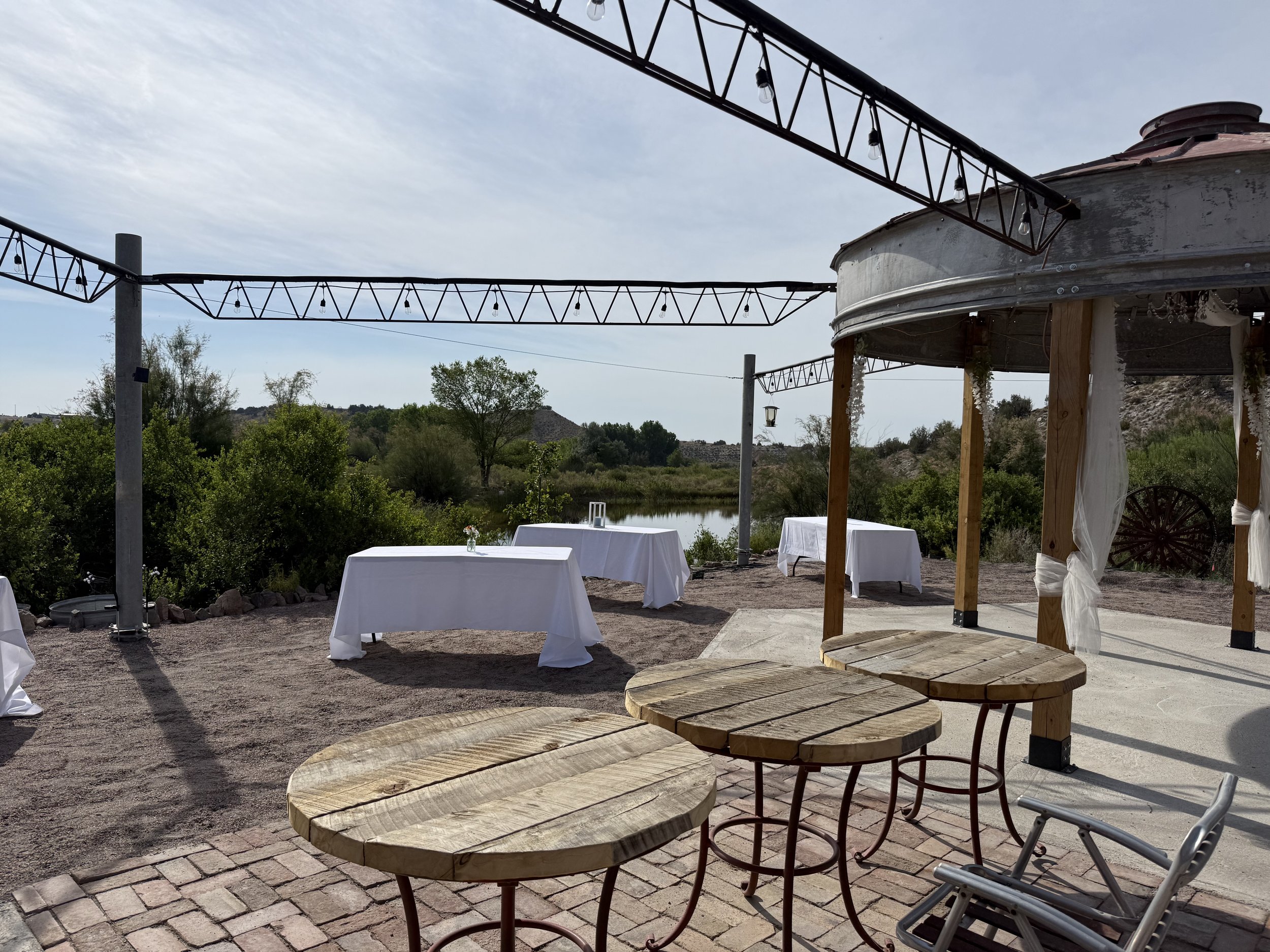The dance floor silo and wedding reception tables set up at Lost Pond wedding venue, the Southern Colorado Outdoor wedding venue has reception seating by the pond under the string lights with a grain silo dance floor.