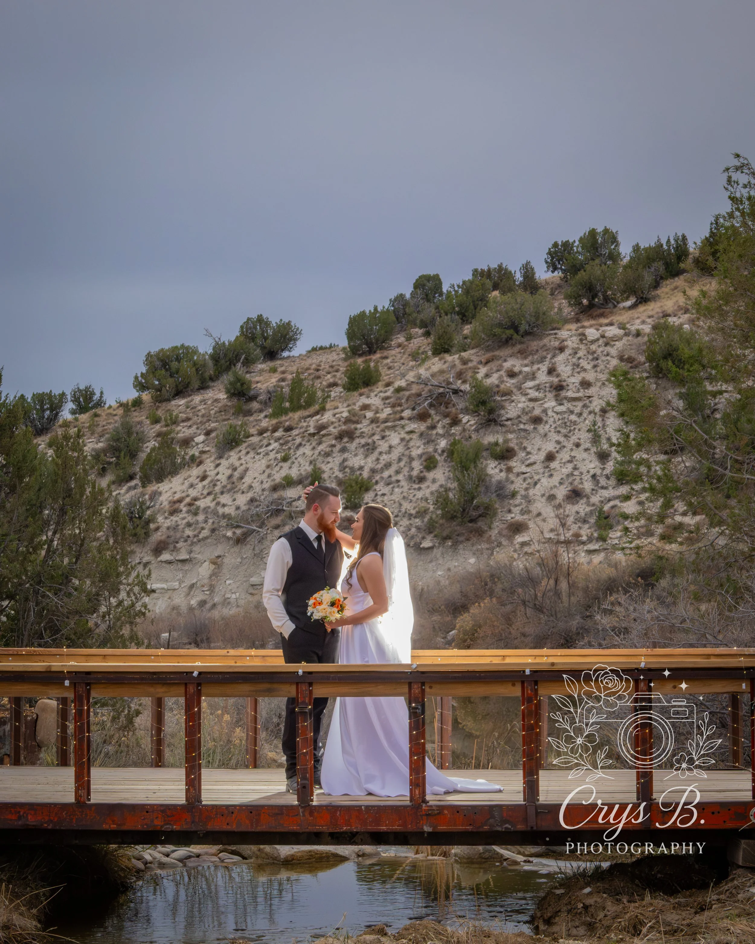 Bridge over the waterfall at Lost Pond wedding venue with bride and groom looking romantically near Canon City, Colorado.