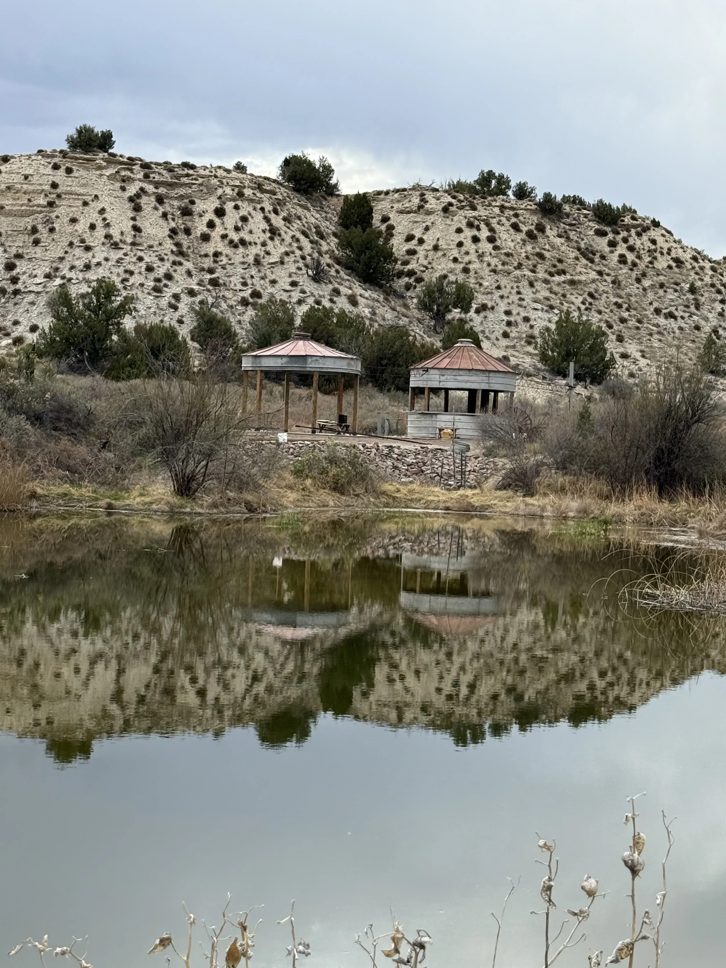 The wedding reception grain bin silo bar and gazebo reflecting on the pond at Lost Pond wedding venue, a rustic outdoor wedding venue with modern touches near Canon City, Colorado.