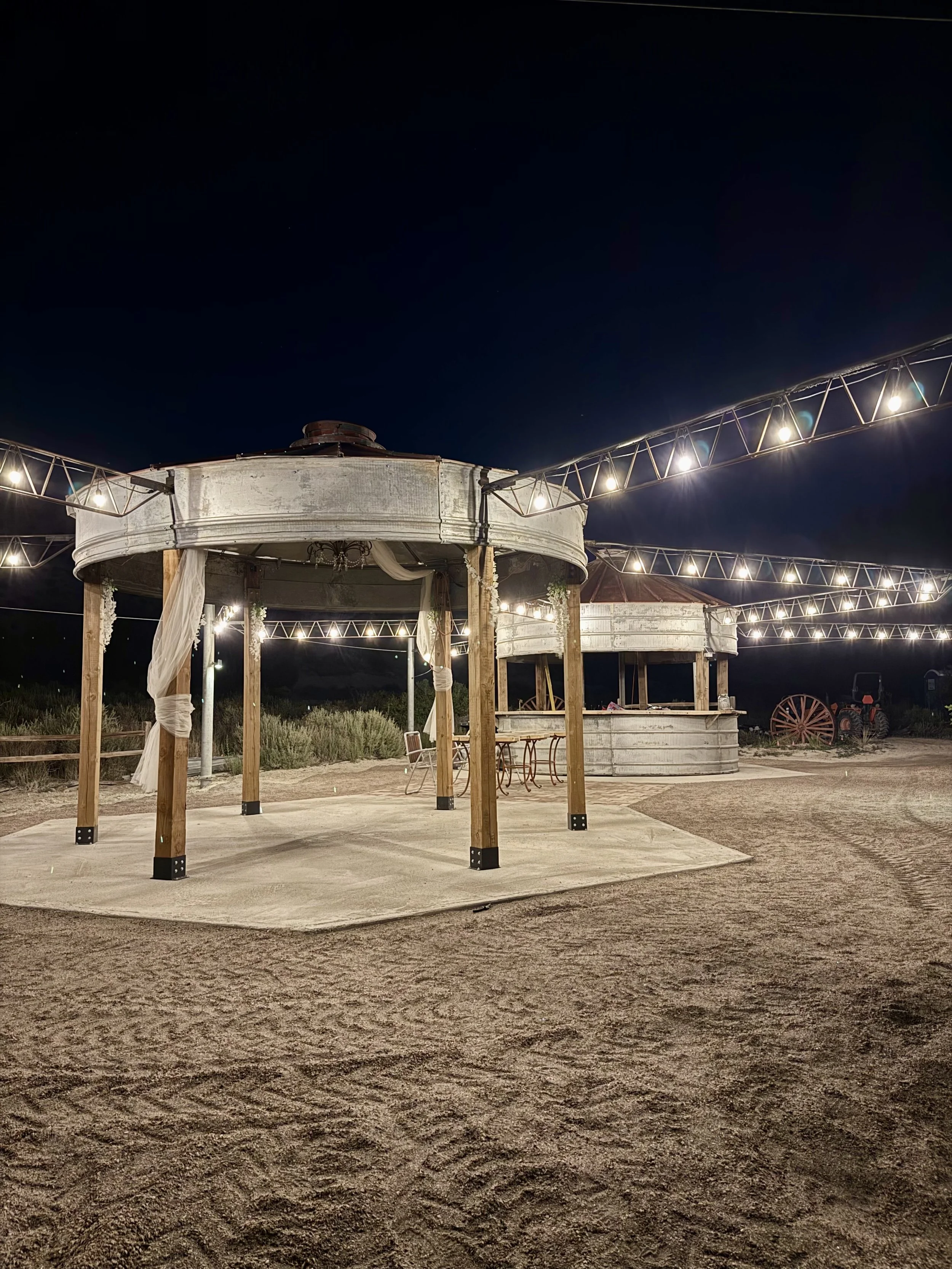 The string lights over the wedding reception area at Lost Pond wedding venue over the rustic silo dance floor. This outdoor wedding venue near Colorado Springs, Colorado features a rustic silo bar and a gazebo dance floor.