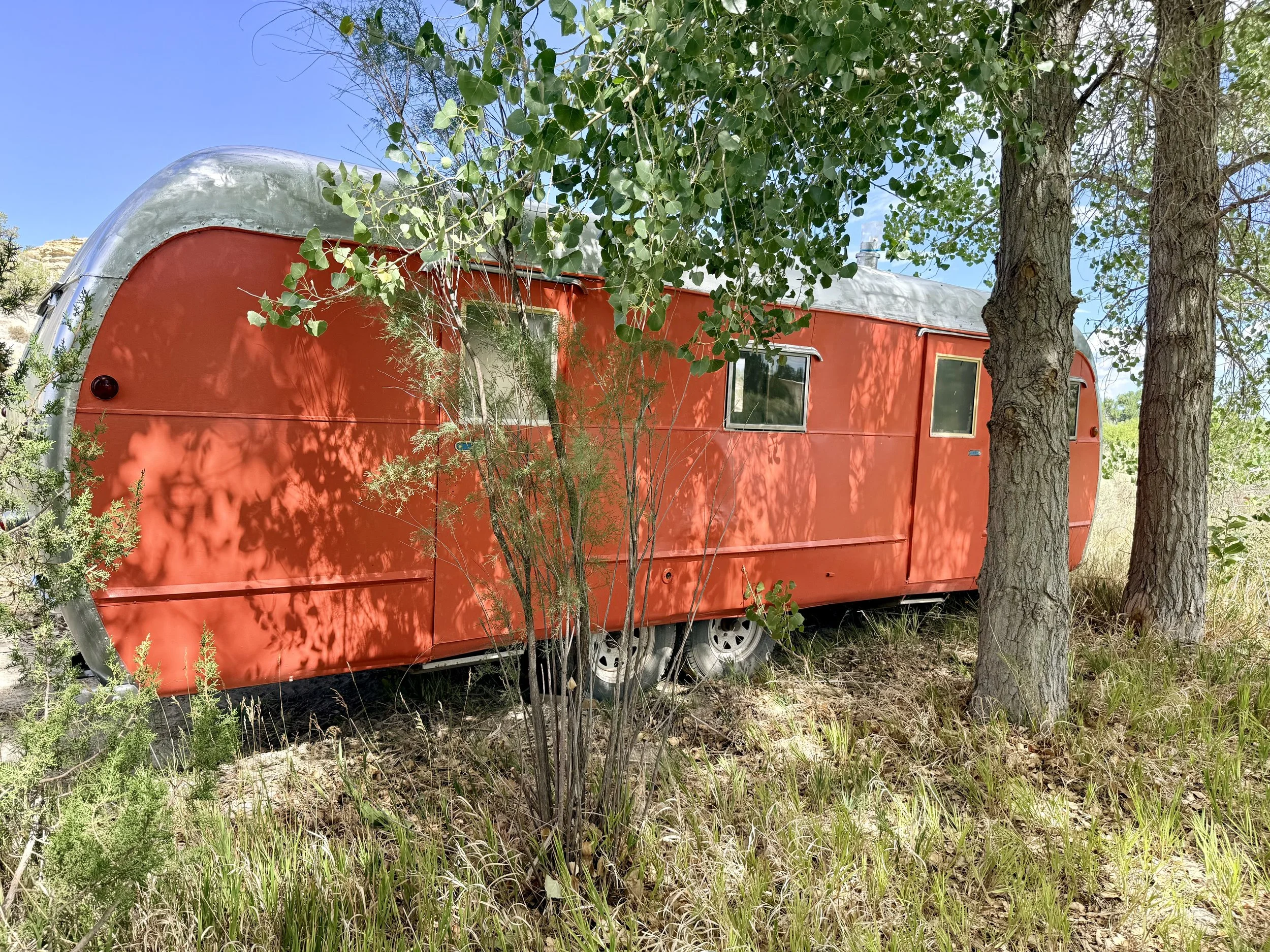 Vintage airstream trailer bridal suite in the mature trees at Lost Pond wedding venue near Florence, Colorado.
