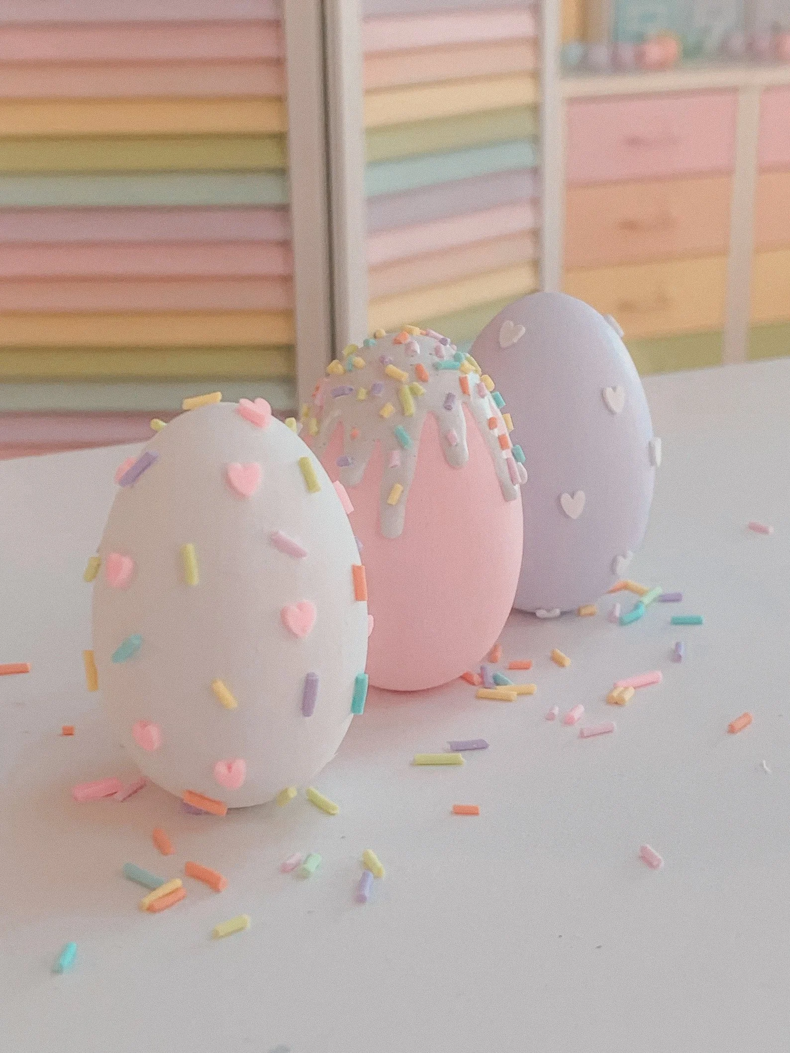 Add a whimsical touch to your Easter decor with these hand-painted pastel eggs from TildaLovesTeddy. Each wooden egg is adorned with white “frosting” and colorful sprinkles, reminiscent of sweet confections. Available in sets of 6 or 7, these eggs co