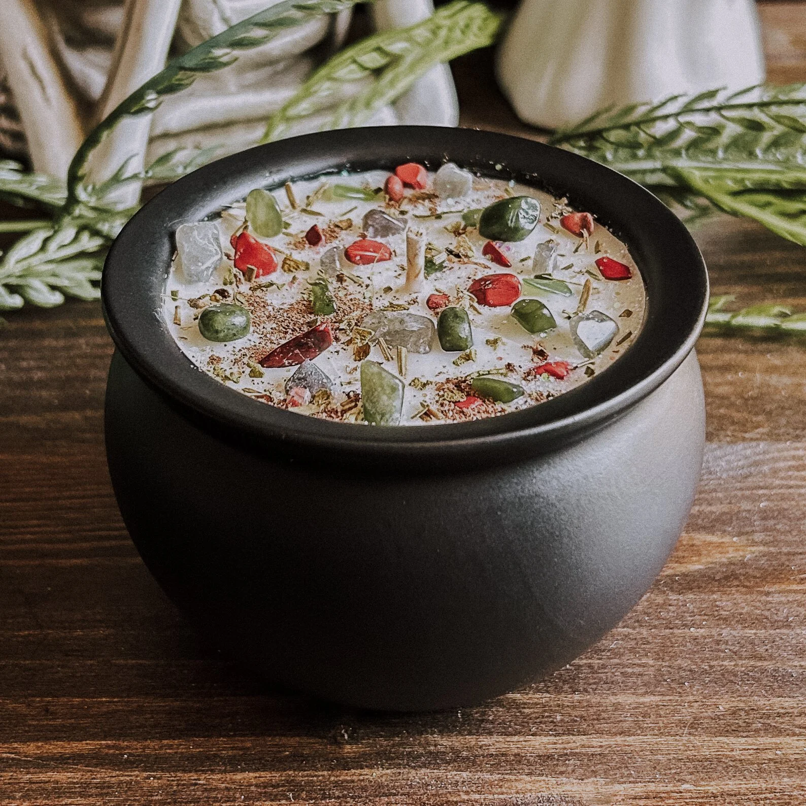 Hand-poured soy candle in a reusable black cauldron, topped with green jade, lepidolite, red jasper crystals, mistletoe, pine, and eco-friendly shimmer. Designed for Yule rituals, winter witchcraft, and cozy seasonal altars.