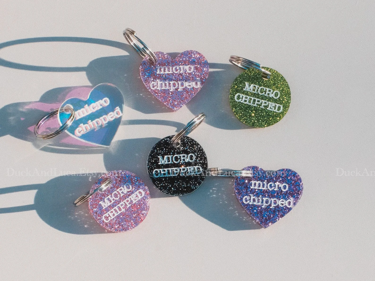 A round acrylic pet tag with “Microchipped” engraved in bold letters. The tag has a clean, modern style and is attached to a silver keyring.