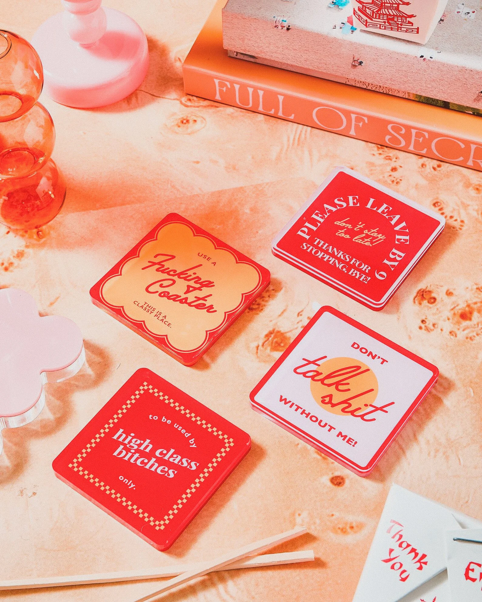 Bold red acrylic coasters with sharp, witty quotes, perfect for maximalist tablescapes and unapologetically sassy drinkers.
