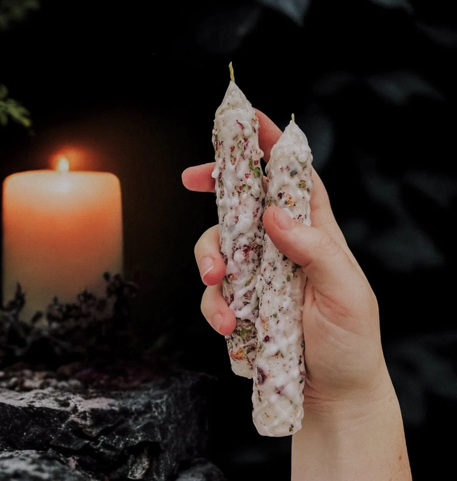 Image description: A white blessings candle decorated with florals and shimmering herbs, styled on a witch’s altar beside selenite and spiritual charms. A calming tool for gratitude and ritual work. Blessings candle Etsy, ritual candle for healing, s