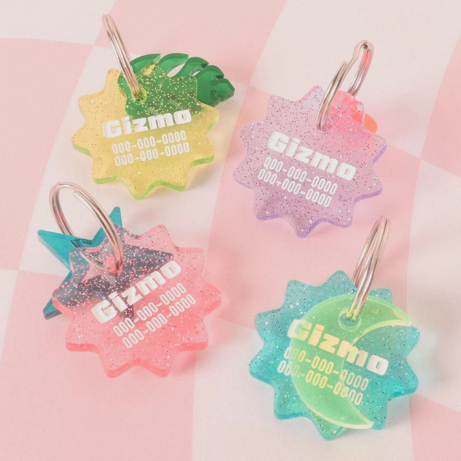 Custom pet ID tags shown in vibrant colors with a sparkly, glittery finish, available in several shapes like hearts, bones, or circles.