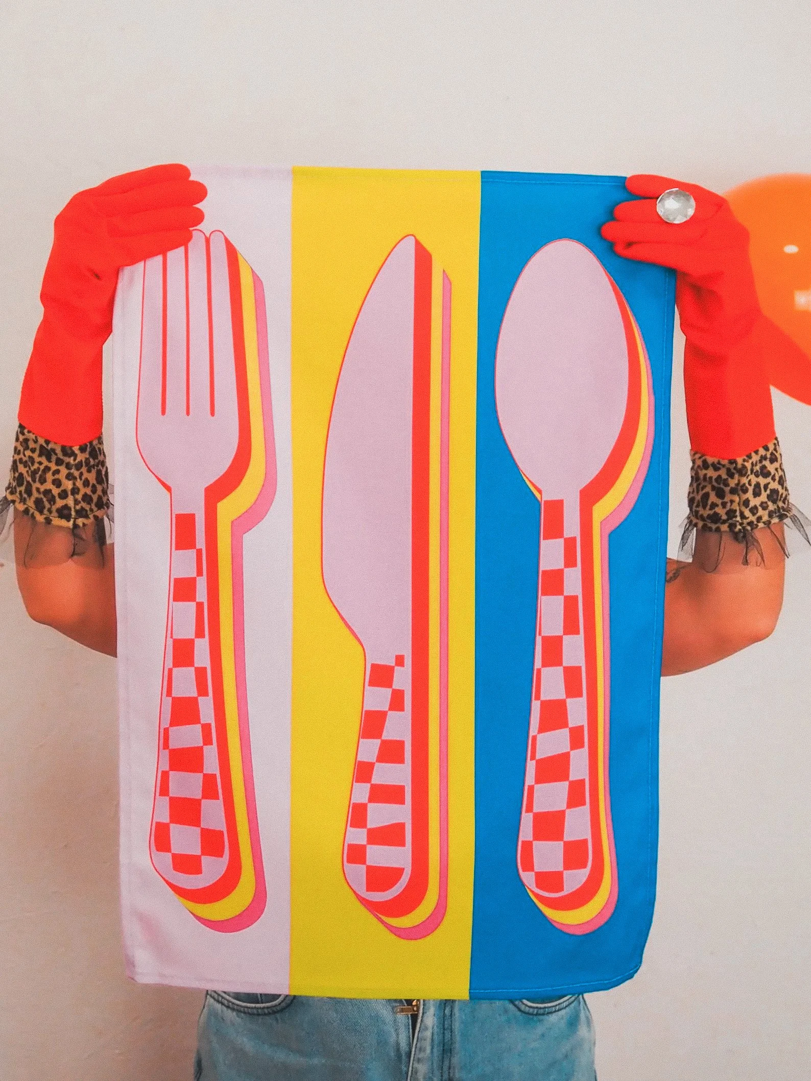 Bright tea towel showcasing neon pink, orange, and blue cutlery on a black backdrop, great for bold kitchens, eclectic cooks, and gifting with flair.