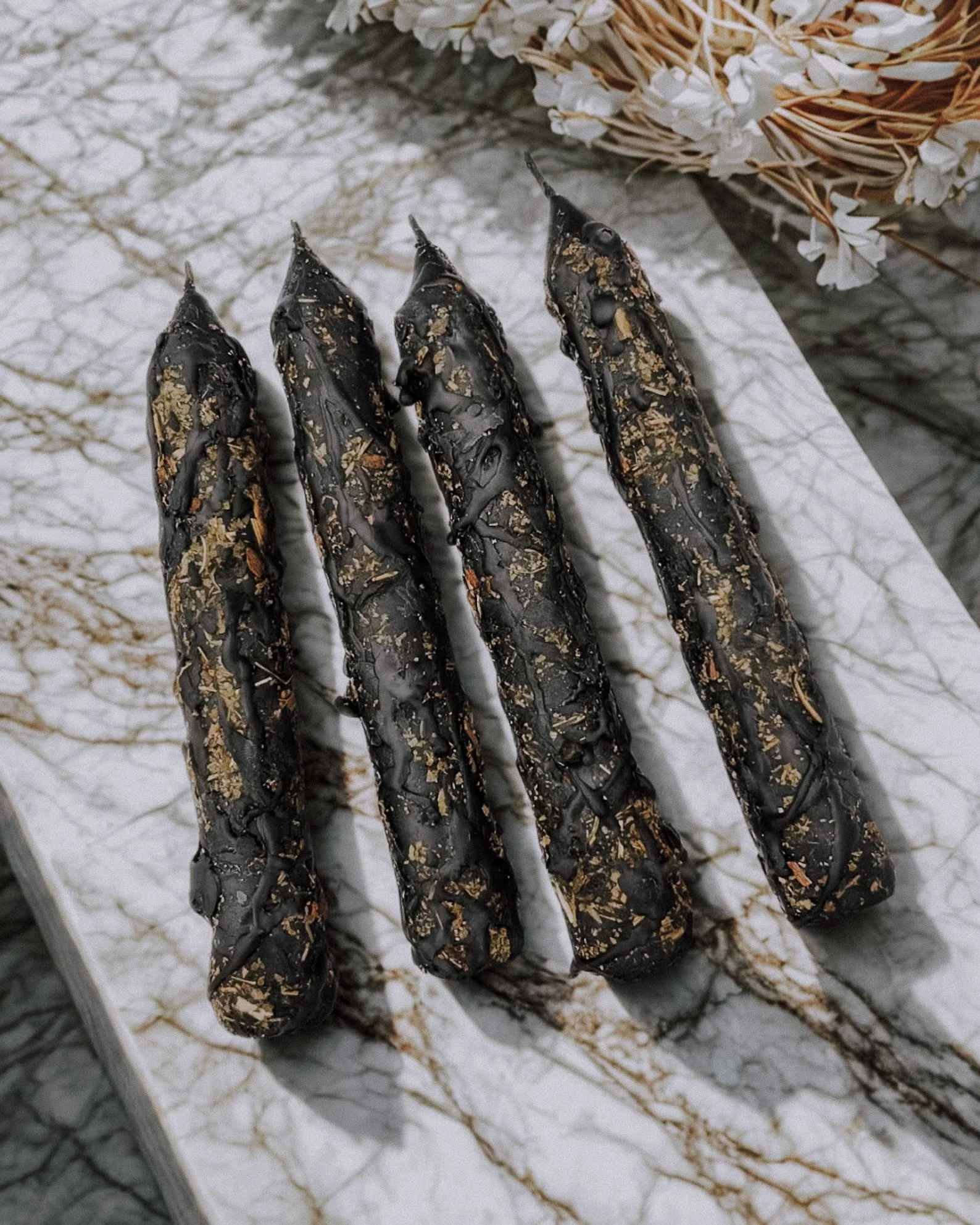 Image description: A black ritual candle labeled “Protection,” topped with herbs and crystals, sits on a dark altar surrounded by witchy tools and dried flowers. A powerful aesthetic piece for spellwork and modern witch decor. Protection candle, hex