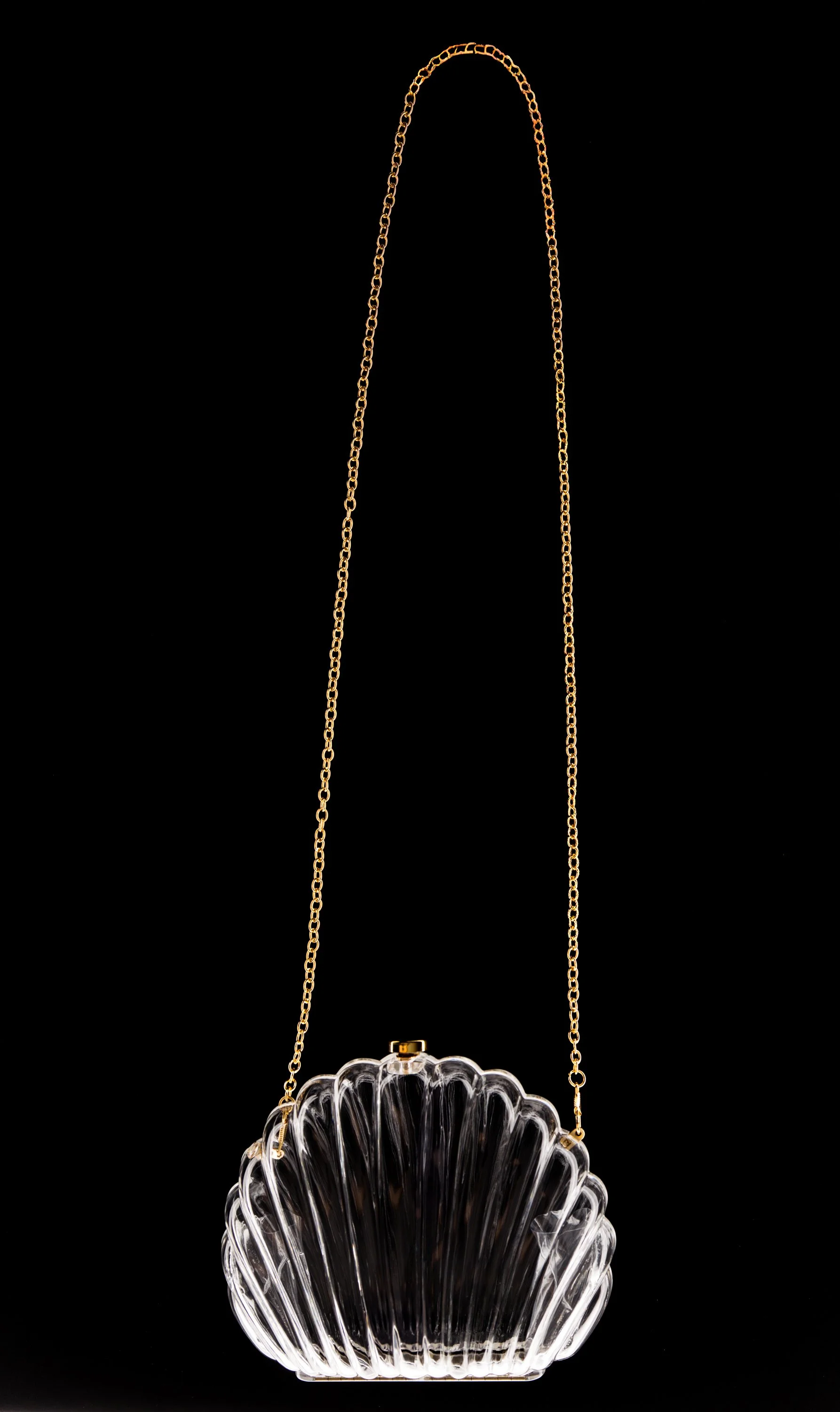 A clear purse with a scalloped design and a gold chain strap.