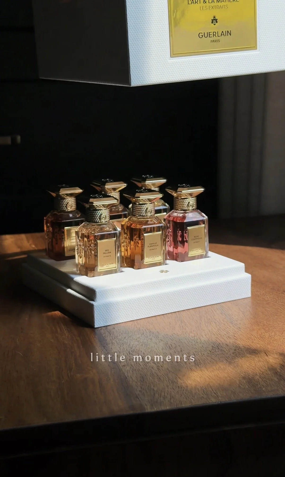 Guerlain L’Art & La Matière extrait fragrances displayed on a wooden table with warm cinematic lighting and luxury editorial styling.