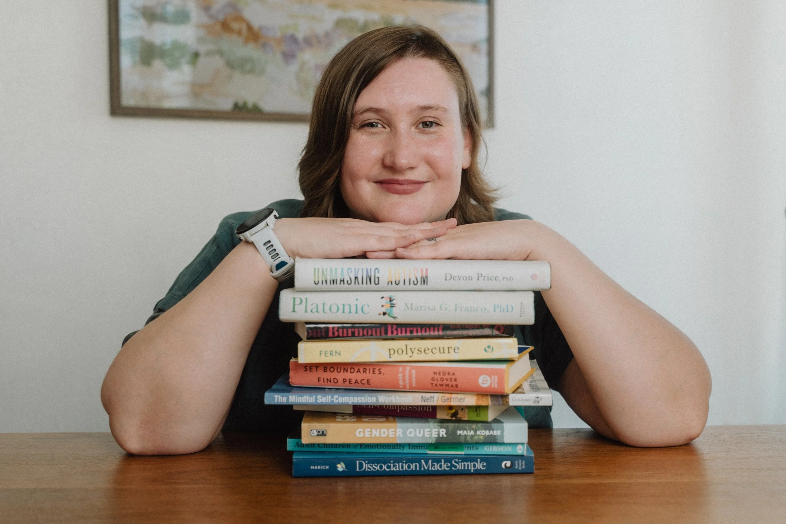 Shayla with her chin on a stack of books, smiling at the camera