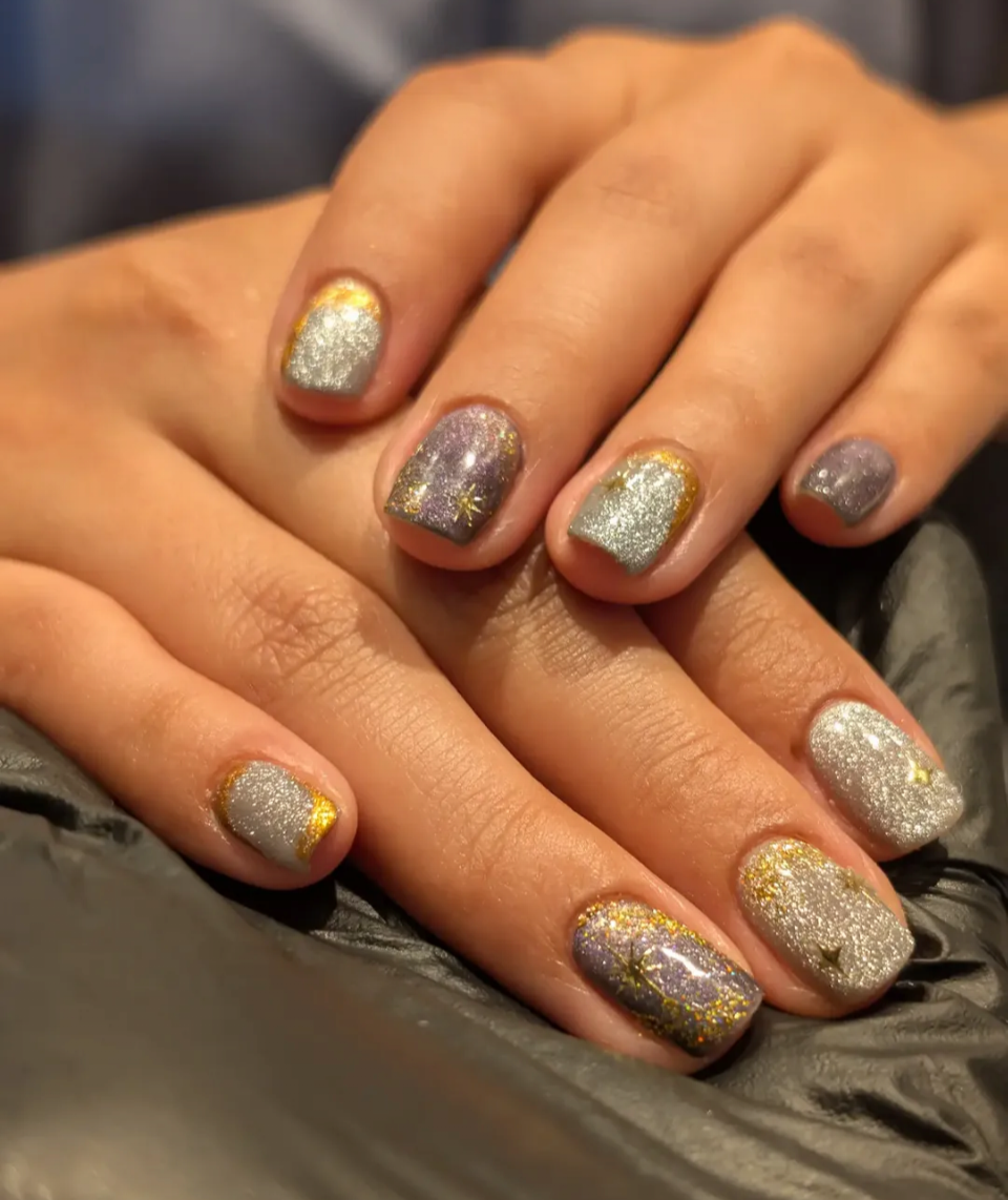 Gel polish nails also known as shellac polish, the nails are a short square on natural nails. The design uses multiple colours of catseye nail polish, silver and dark purple, with isolated chrome designs and nail stickers