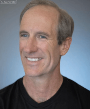 Professional headshot of a middle-aged man with short gray hair, blue eyes, and a friendly smile, wearing a black shirt, photographed against a plain blue background.