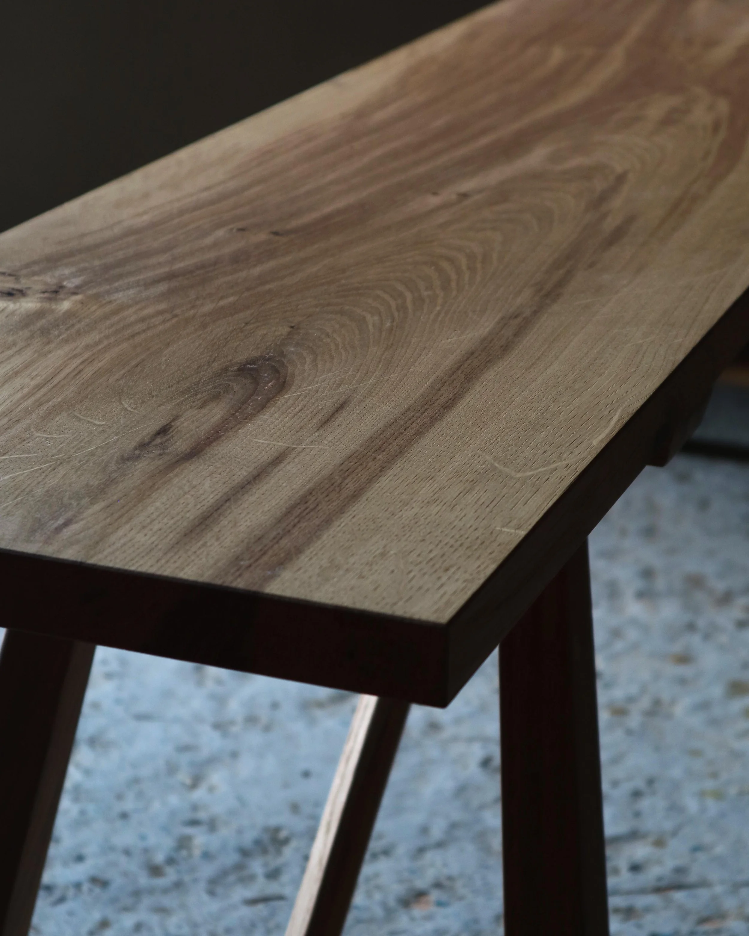 Close o
up of the wild British oak grain on the bench top of the Le Coubre bench made from locally sourced British oak with traditional farmhouse design and curved rail detail