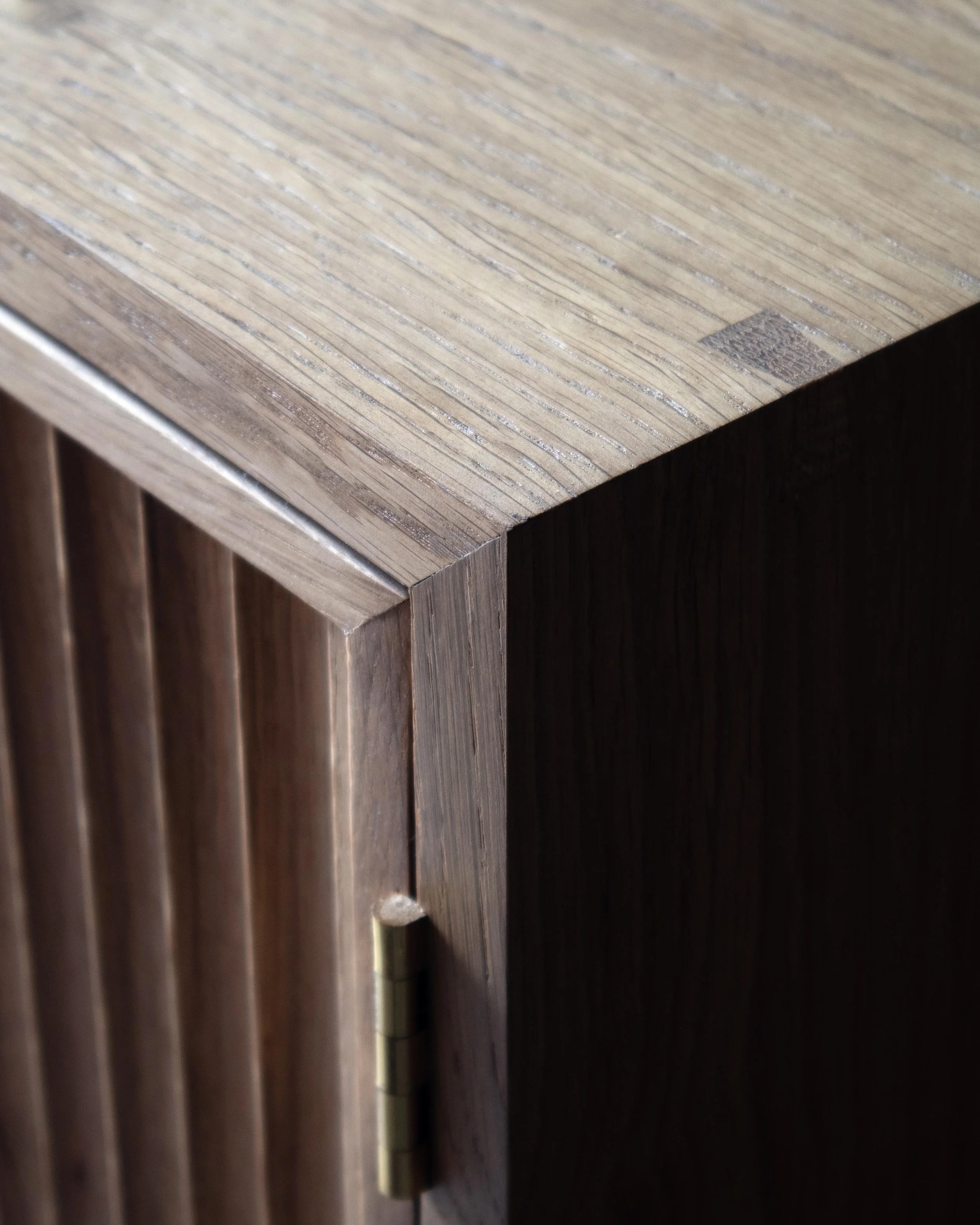Handcrafted Flauta cabinet in solid oak with fluted front panels, natural and fumed oak contrast, brass detailing, and octagonal legs