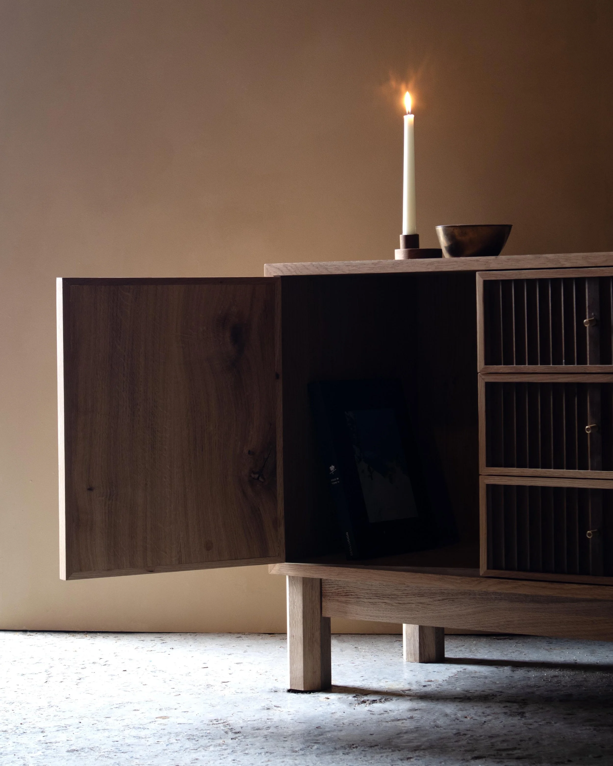 Handcrafted Flauta cabinet in solid oak with fluted front panels, natural and fumed oak contrast, brass detailing, and octagonal legs