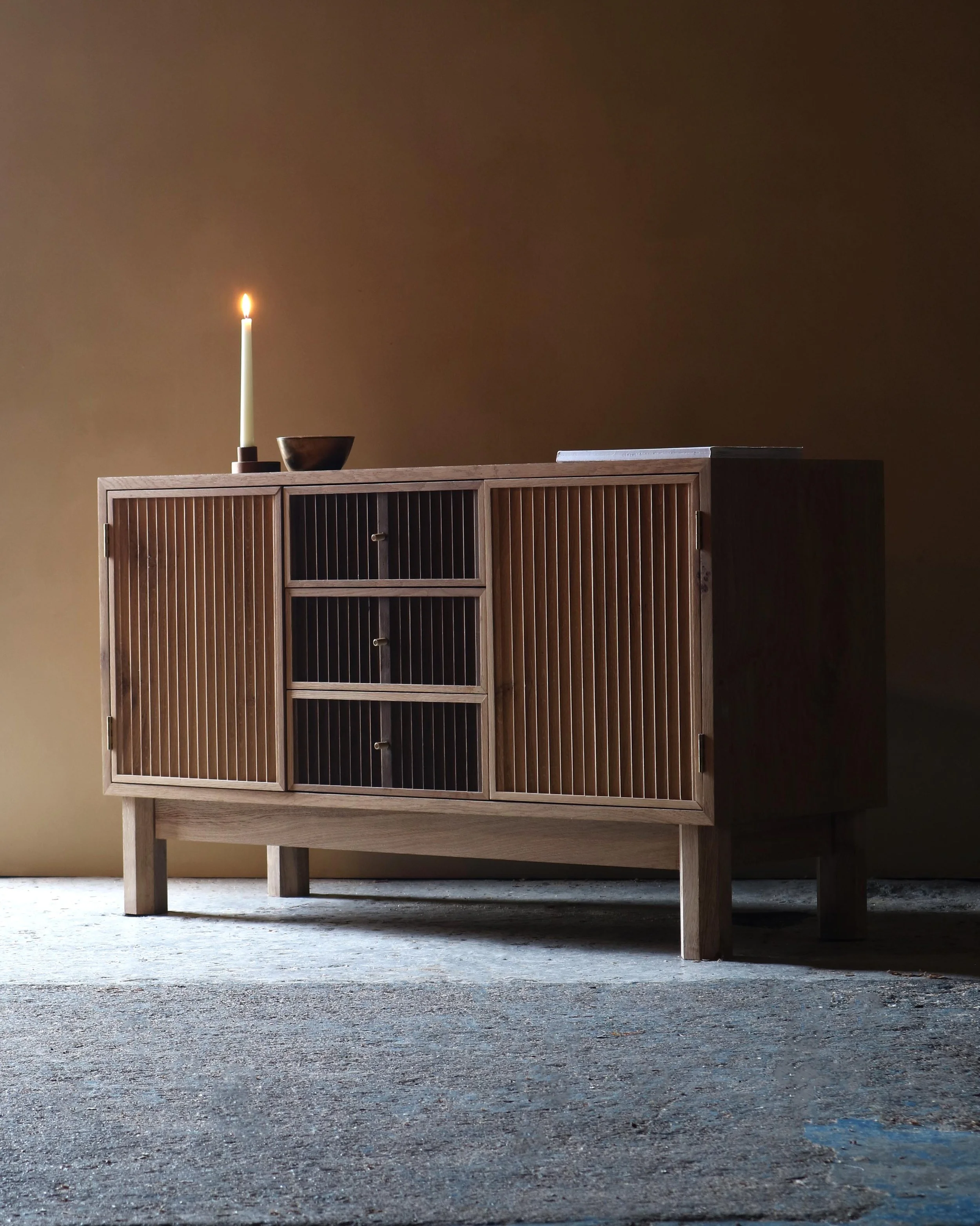 Handcrafted Flauta cabinet in solid oak with fluted front panels, natural and fumed oak contrast, brass detailing, and octagonal legs